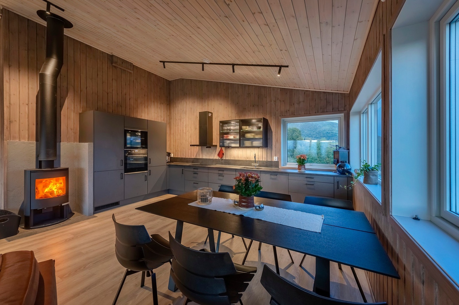 Kjøkkeninnredning med glatte mørke fronter og integrerte hvitevarer som: platetopp, stekeovn, oppvaskmaskin, kjøl- og fryseskap. Galleribilde