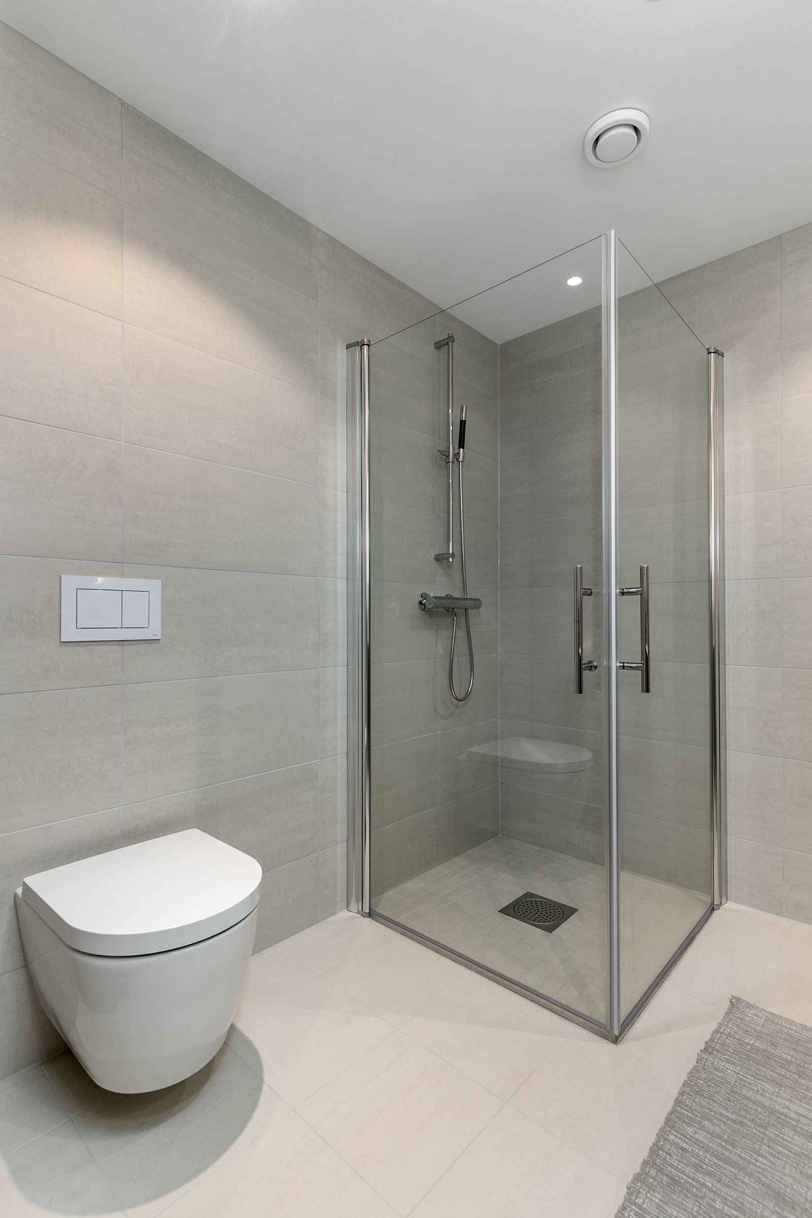 Rette dusjvegger i herdet glass, som kan slås inn mot vegg og med profiler i krom. Vegghengt toalett. Galleribilde