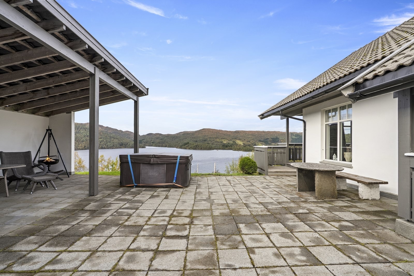 Mellom hytta og carporten er det ein fint opparbeida tun med dekke av betongheller og overbygd uteplass Galleribilde