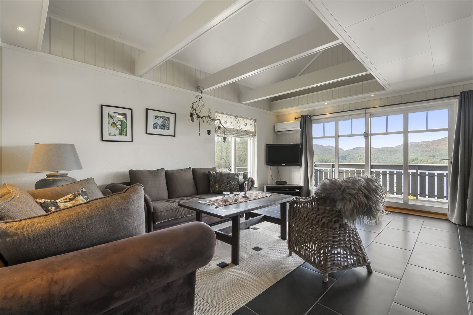 Stova er av god størrelse med ekstra takhøgde og store vindu/terrasse-dør ned mot vatnet Galleribilde