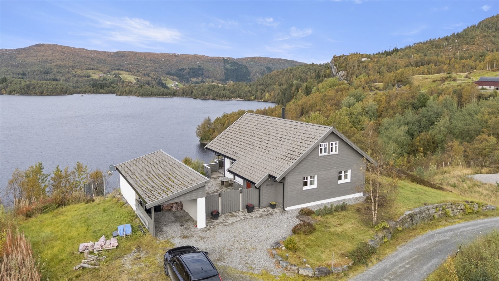 Eigedommen har ei fint opparbeida tomt med god parkeringdekning, hage med plen, støttemurar i naturstein og skjema uteplass mellom hytta og carporten Galleribilde
