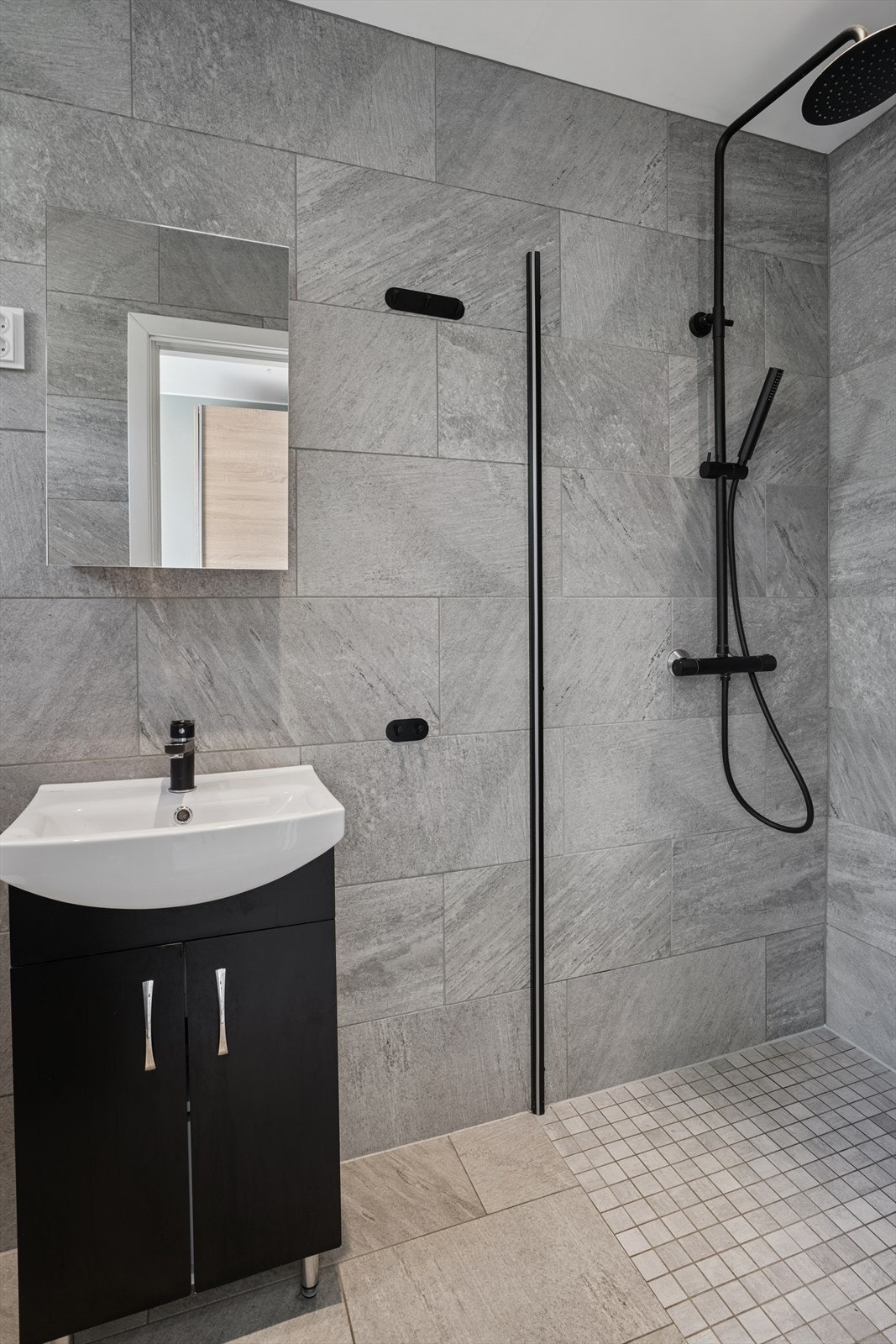 Delikat flislagt baderom med gulvvarme. Innredning med servant, wc og et dusjhjørne. Galleribilde