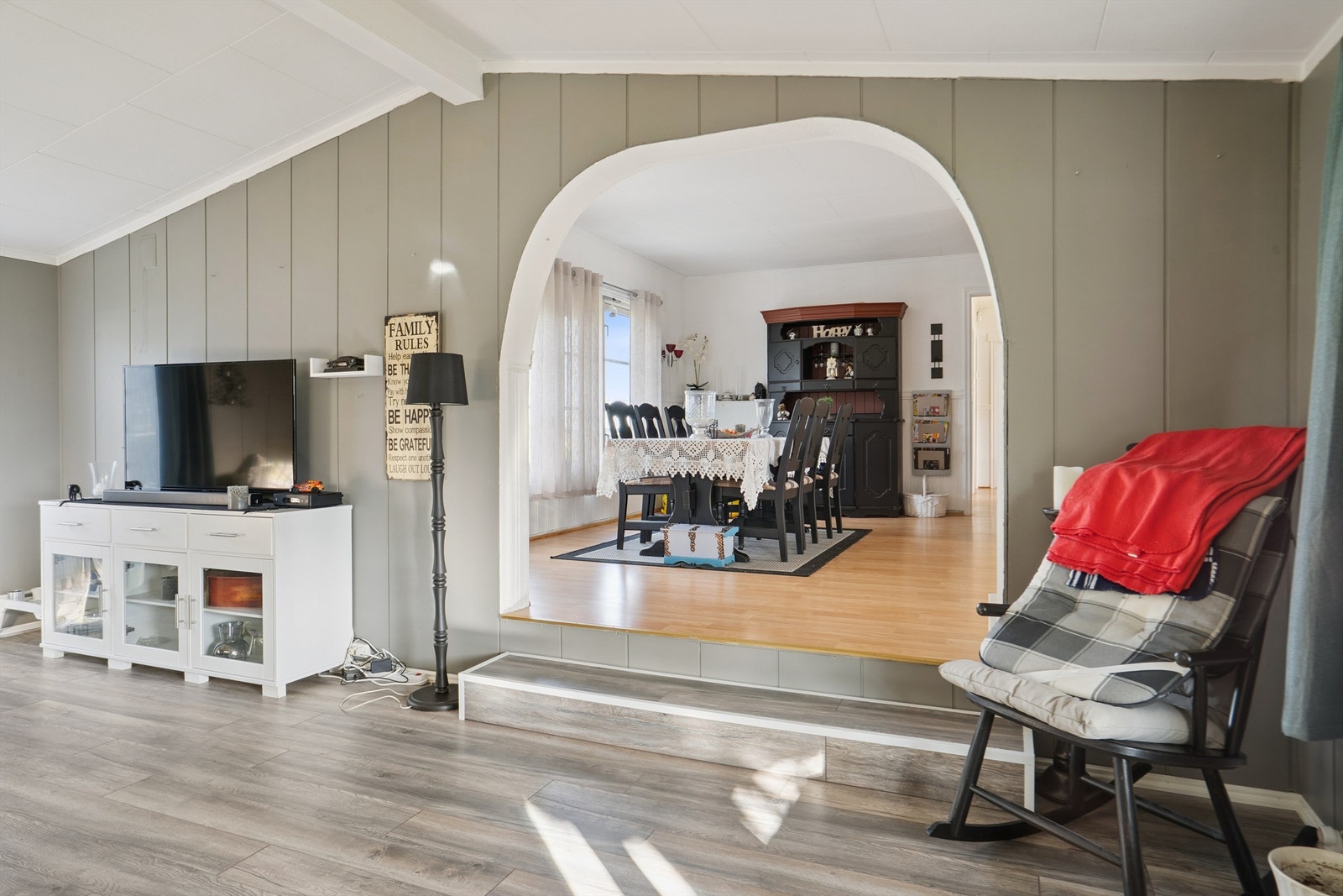 En bueåpning med et lite nivåskille leder inn til stuen i tilbygget. Galleribilde