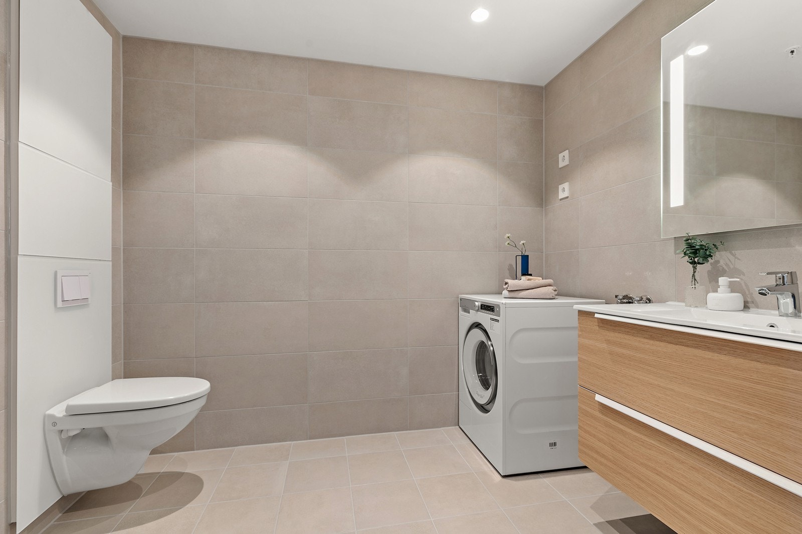 Stilrent og moderne bad med lyse fliser, varmekabler i gulv og en utstrakt bruk av downlights i himling. Galleribilde