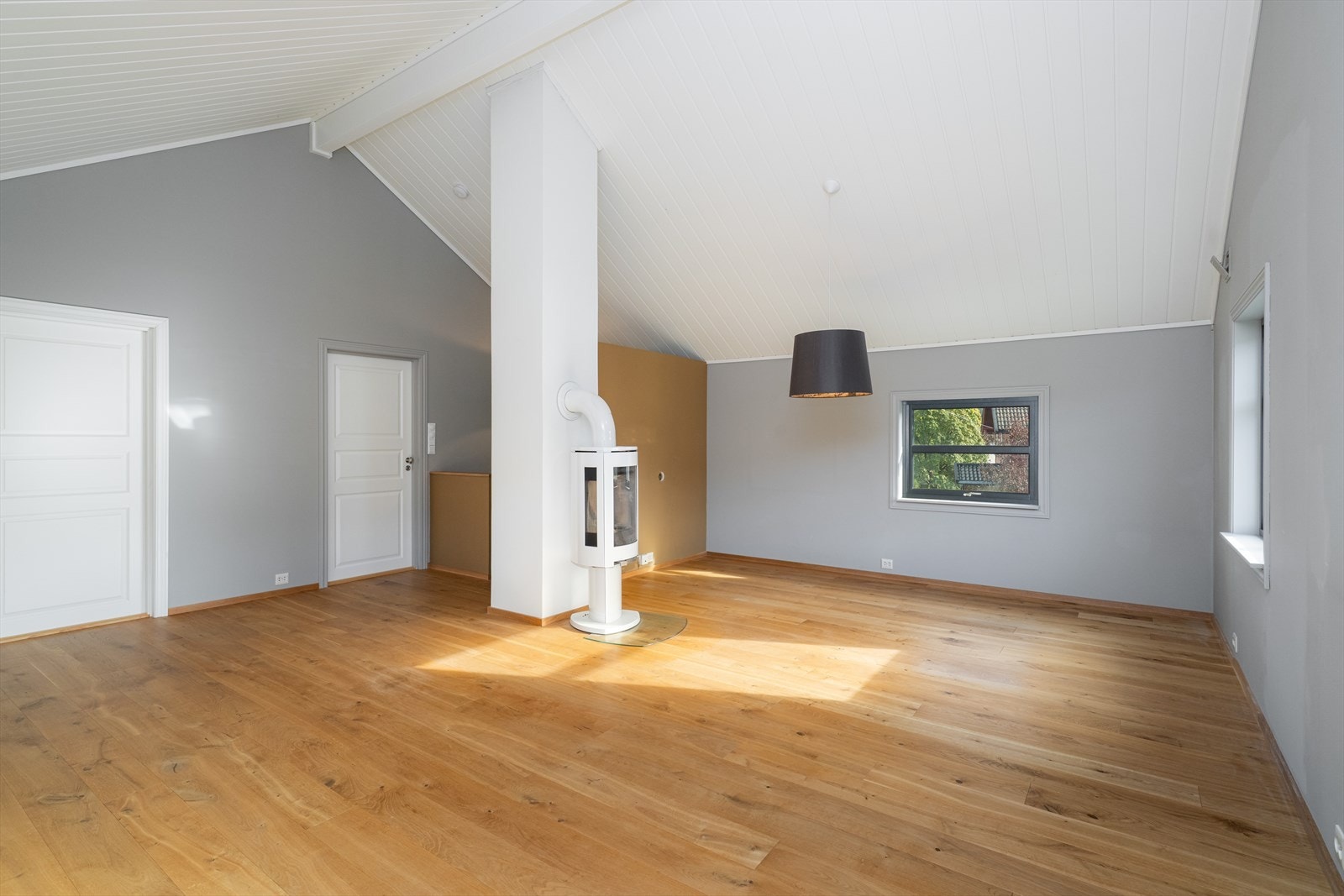 Stua har gode møbleringsmuligheter, og sentralt i rommet er det etablert en moderne vedovn med glassfelt på flere sider. Galleribilde