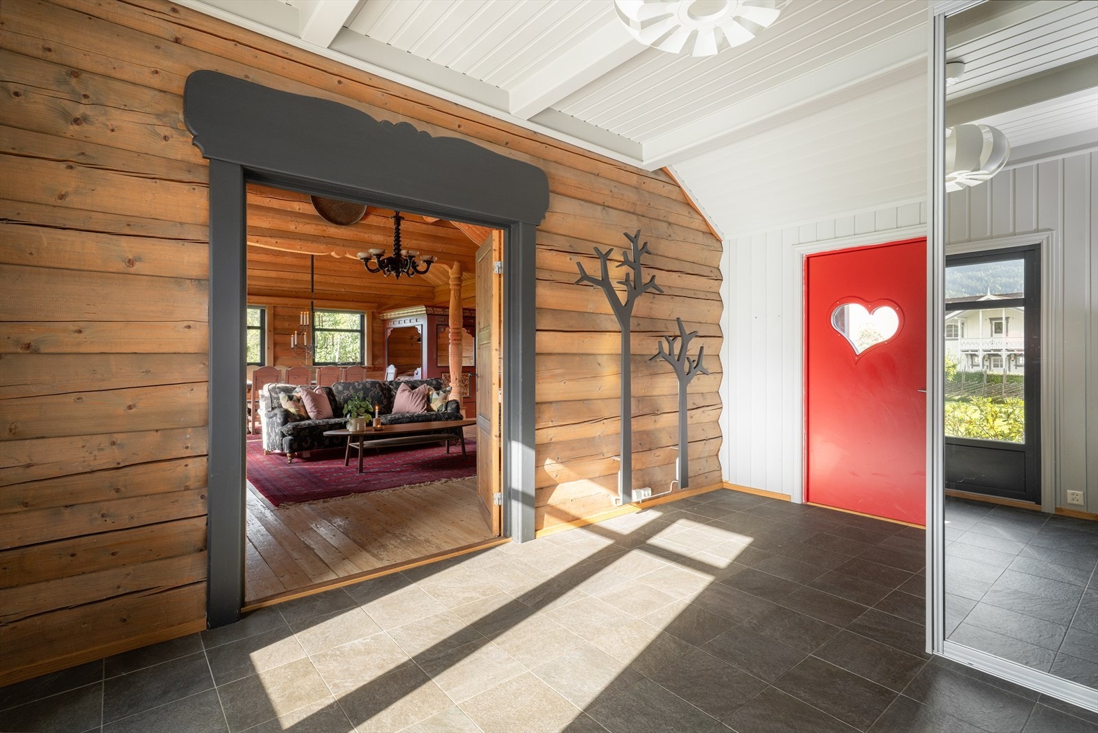 Det romslige gangarealet har flislagt gulv med varmekabler, og beiset laft på vegg kombinert med moderne panel som gir rommet et spennende uttrykk. Galleribilde