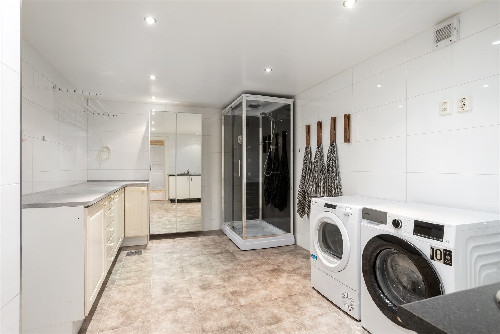 Innredet med servant skap med nedfelt stål skyllekum, skap med arbeidsbenk og dusjkabinett. Galleribilde