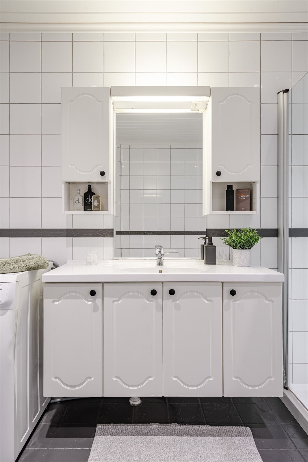 Baderommet er utstyrt med dusjkabinett, servant nedfelt i skapinnredning og speil med belysning. Galleribilde