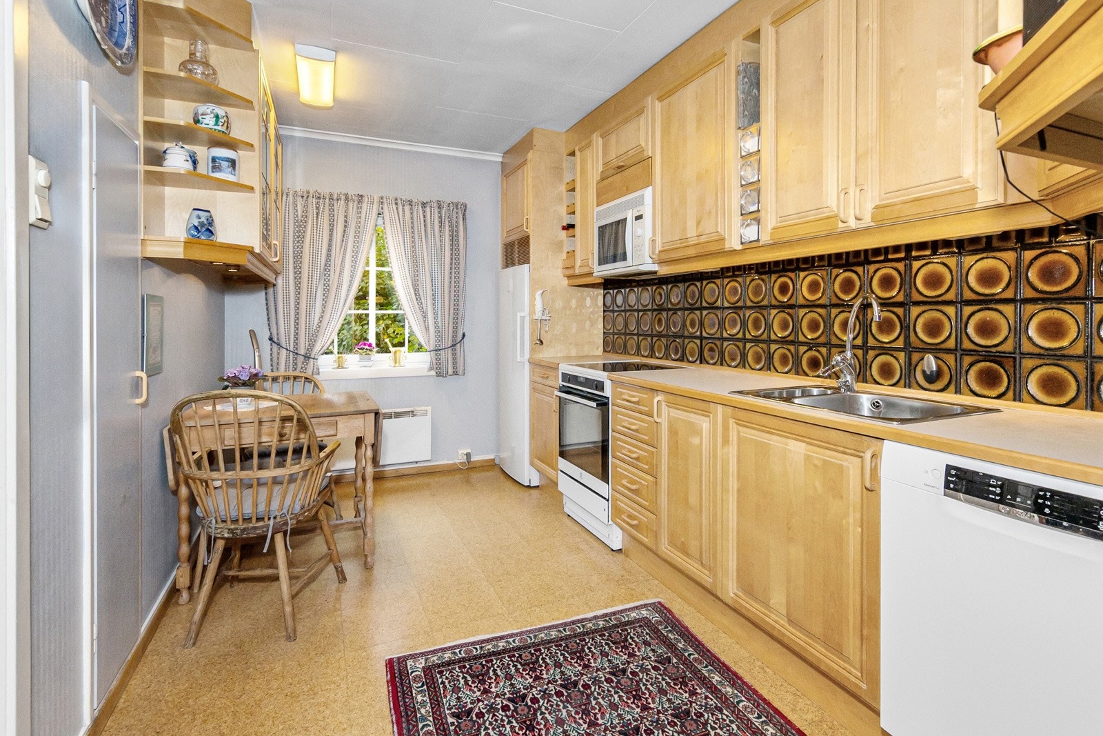 Kjøkkenet har takhøye overskap og godt med oppbevaringsplass i skuffer og skap. Frittstående kjøleskap, komfyr og oppvaskmaskin medfølger i handelen. Galleribilde