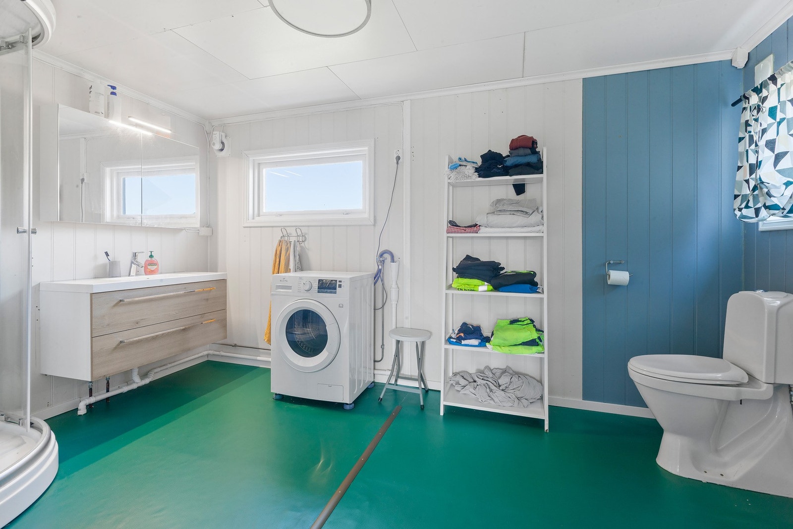 Badet har innredning med nedfelt servant og skuffer under, speilskap med lys over, dusjkabinett, toalett og opplegg for vaskemaskin. Galleribilde