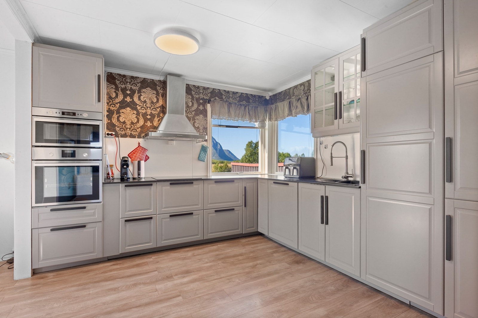 Pen kjøkkeninnredning med grå profilerte fronter, godt med skuffer og skap og god benleplass. Galleribilde