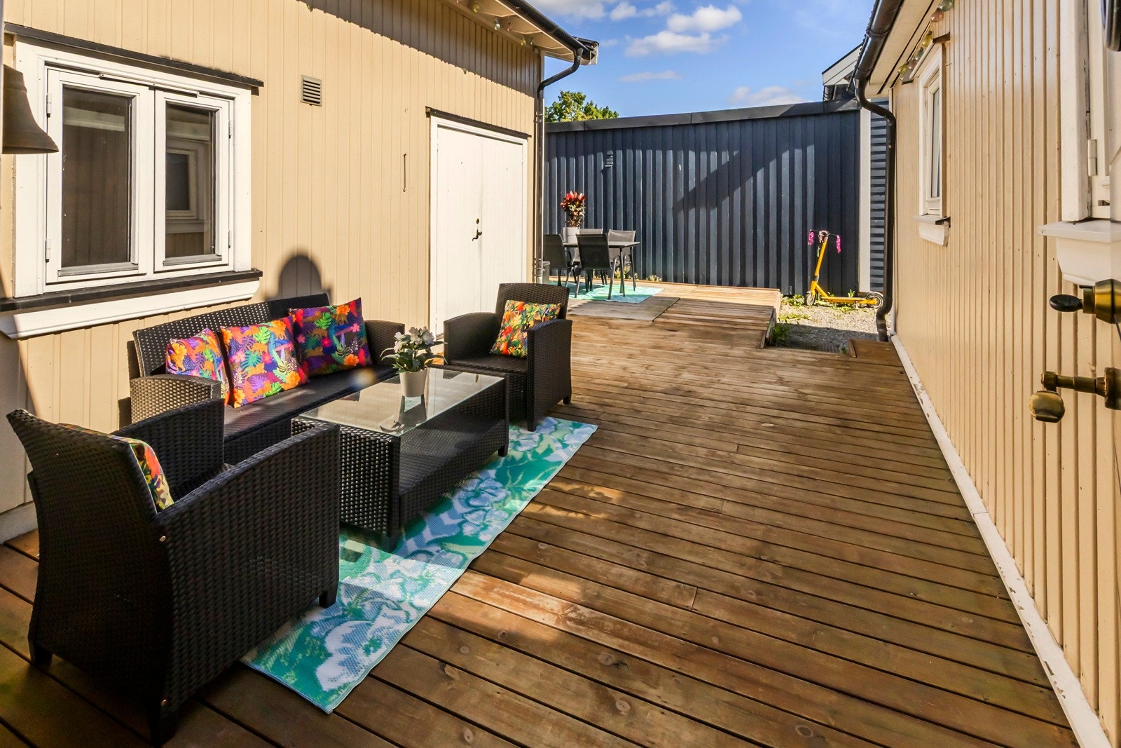 Koselig uteplass med treplatting mellom hovedhus og tilbygg. Galleribilde