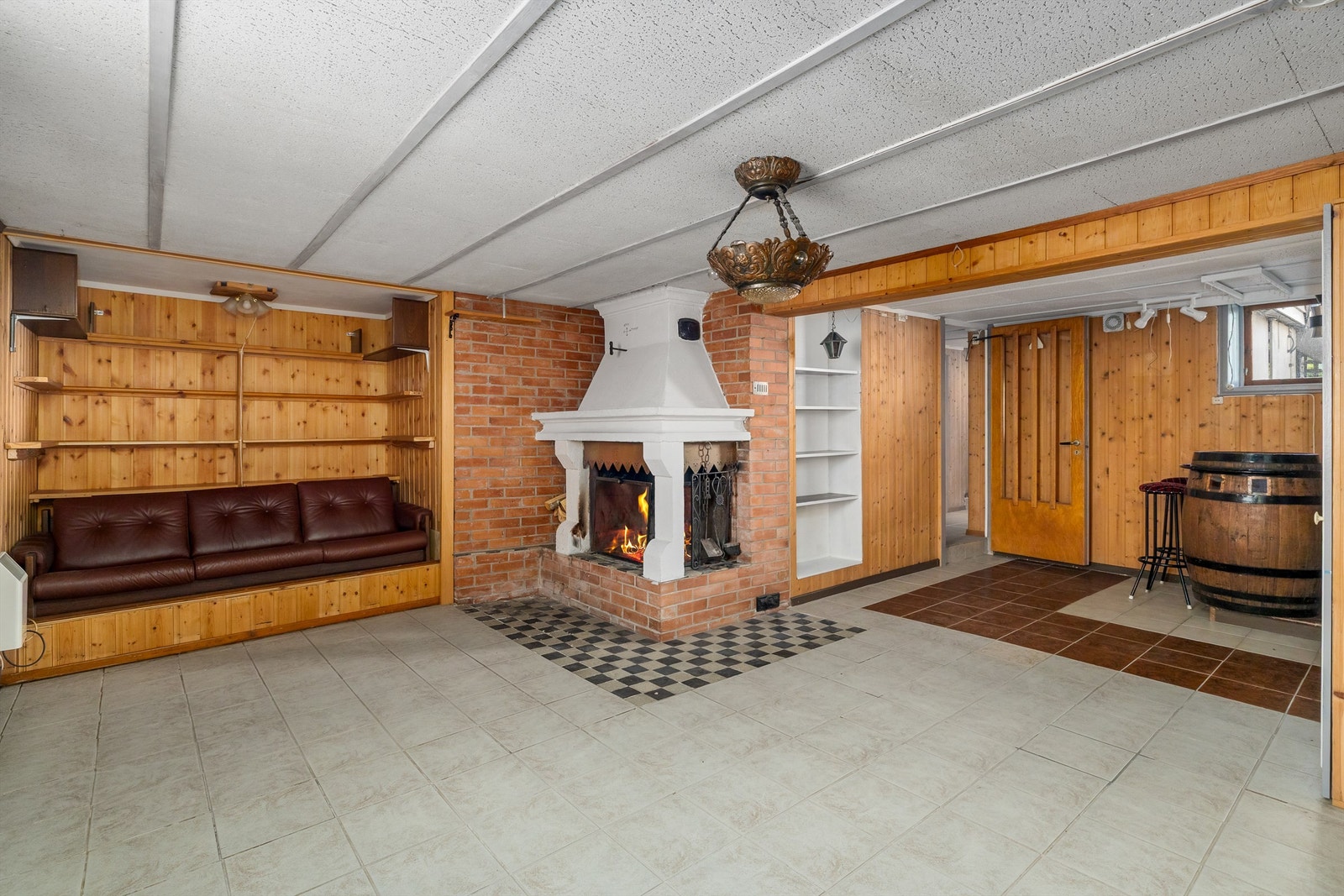 Stor kjellerstue med teglsteinsinnsats og peis. Galleribilde