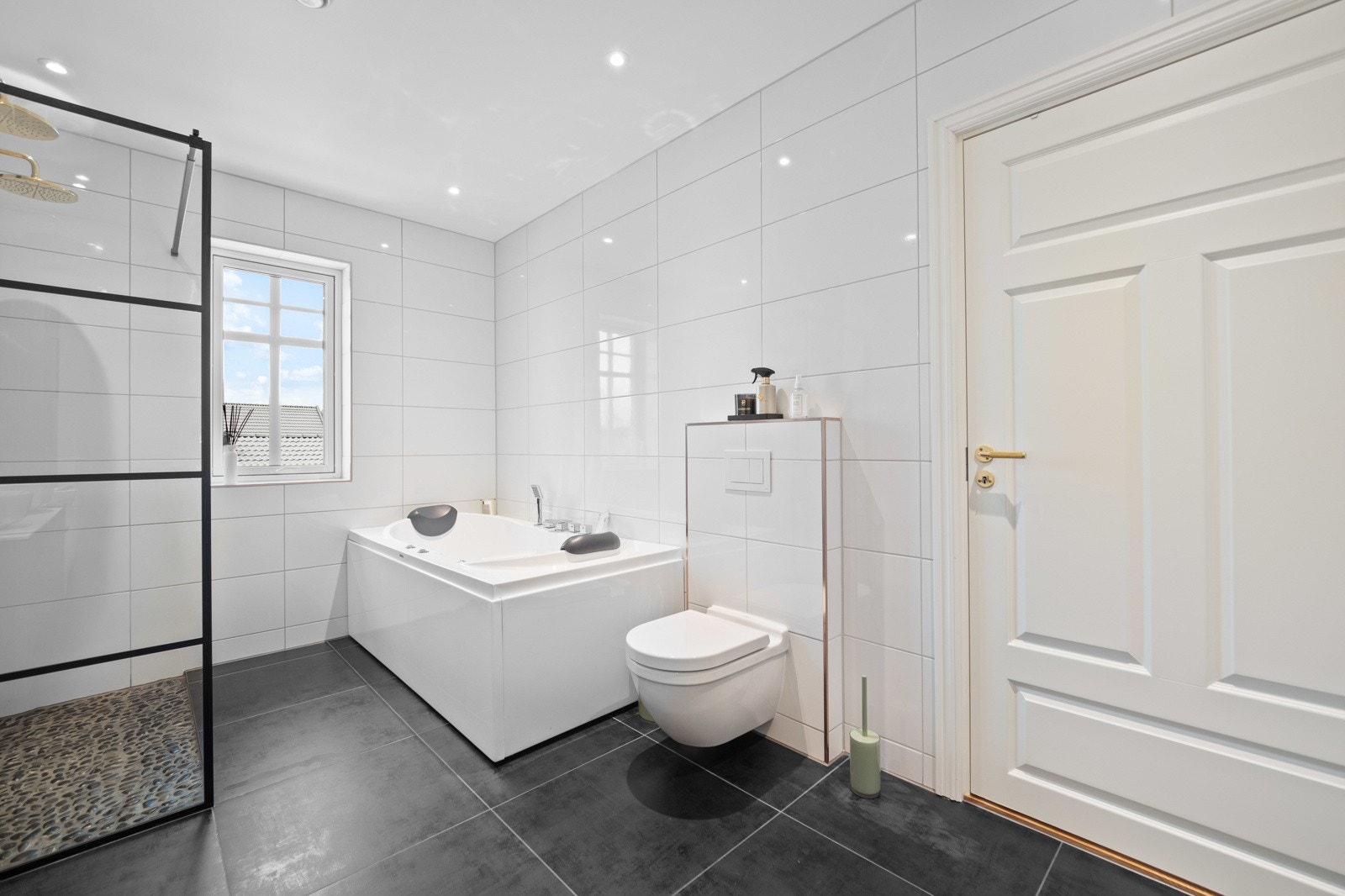 Det er lagt elvesteiner på gulvet i den doble dusjnisjen og montert glassvegg med sort omramming. Galleribilde