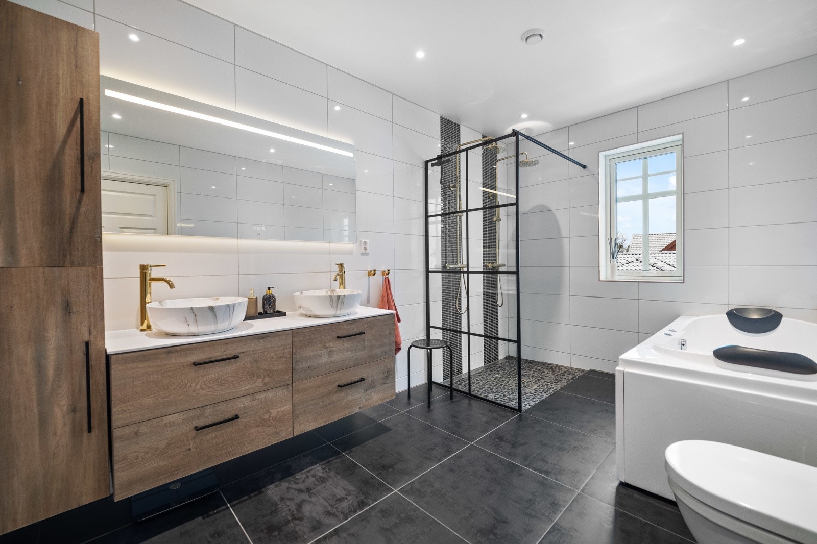 Familiebadet i andre etasje fremstår som en luksuriøs velværesone med både dobbel regnfallsdusj og massasjebadekar. Galleribilde