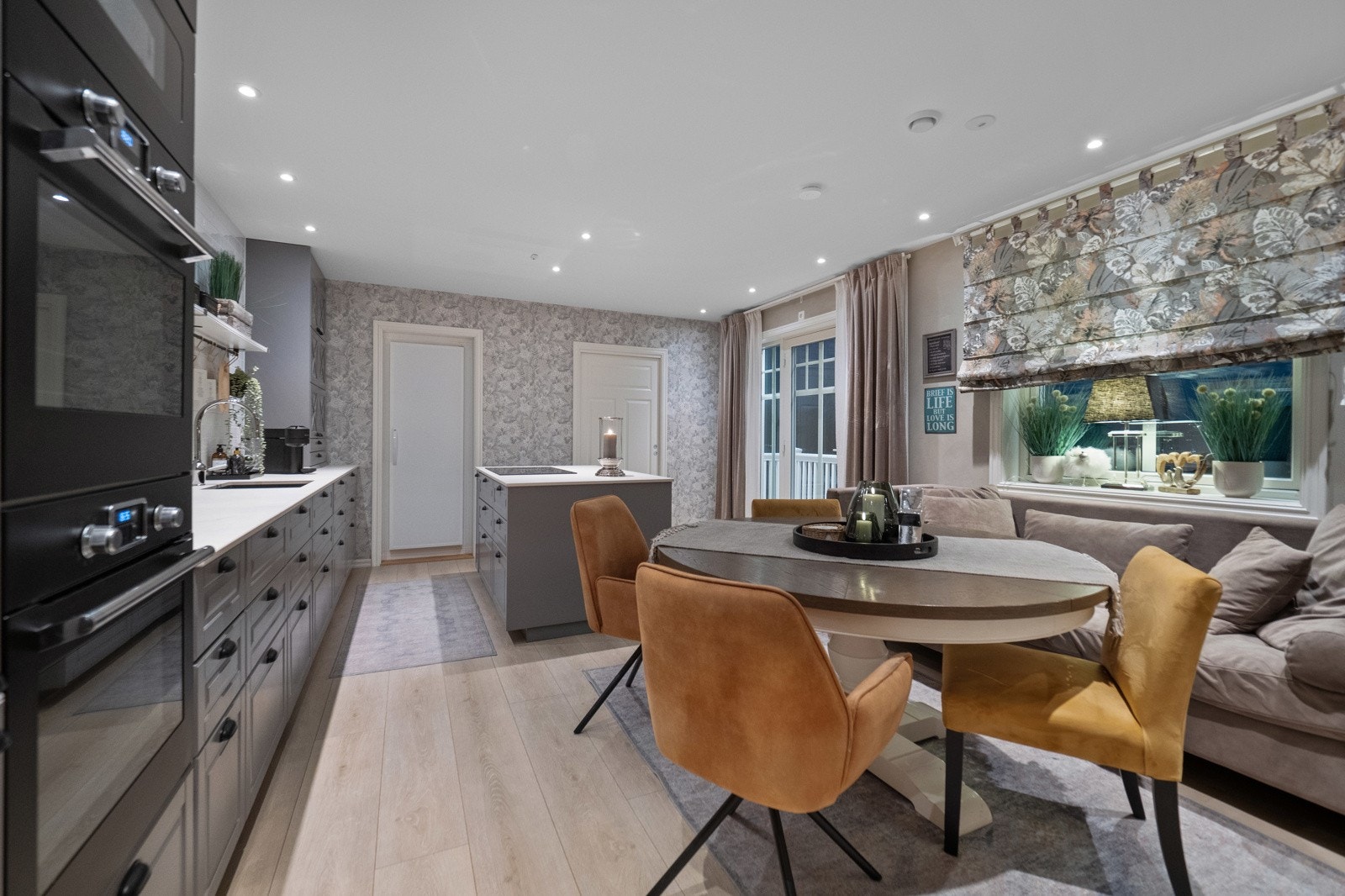 Kjøkkenet har benkeplate i lys glasskompositt, integrerte hvitevarer og adkomst til kjølerom. Galleribilde