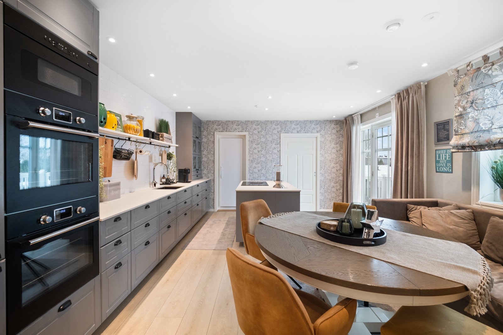 Kjøkkenet har innredning i klassisk stil med grå fronter, benkevitrine, sorte detaljer og godt med oppbevaringsplass. Galleribilde