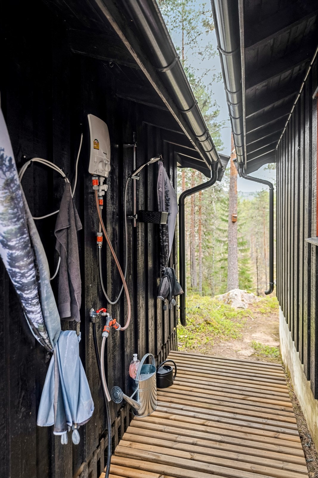 Mellom anneks og hytte er det platting med spilegulv, veggdusj og vannvarmer på vegg. Galleribilde