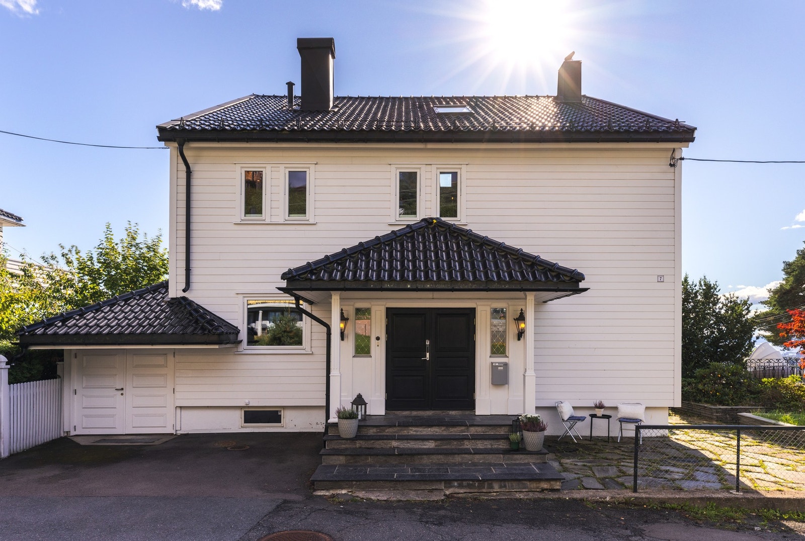 Tomten er pent opparbeidet med plen, prydbusker og terrasseplattinger som inviterer til avslapning og sosialt liv.