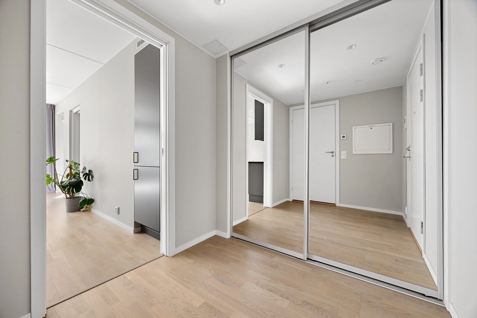 Romslig entré med stor skyvedørsgarderobe fra gulv til tak med speilfronter. Galleribilde