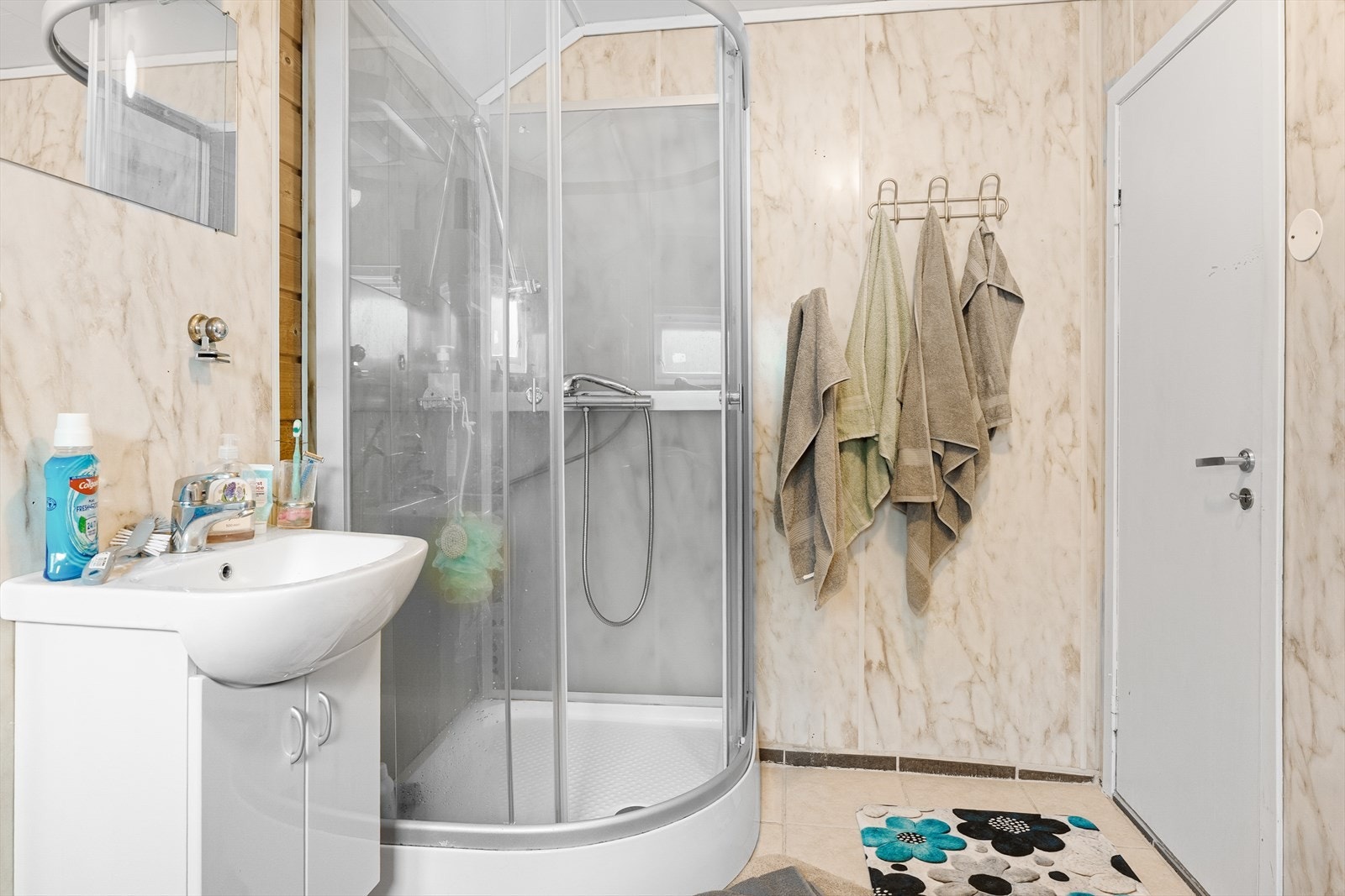 Badet er innredet med toalett, hvit baderomsinnredning og dusjkabinett Galleribilde