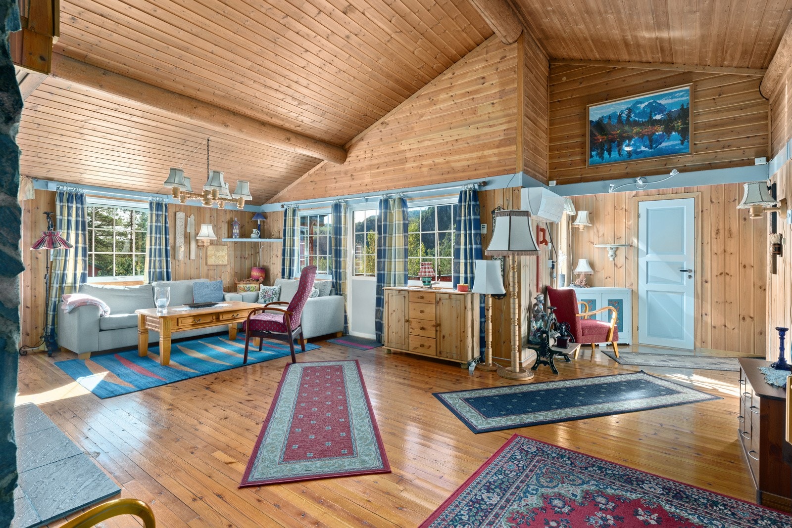 Romslig stue med store vindusflater som slipper rikelig med naturlig lys inn i hytten Galleribilde