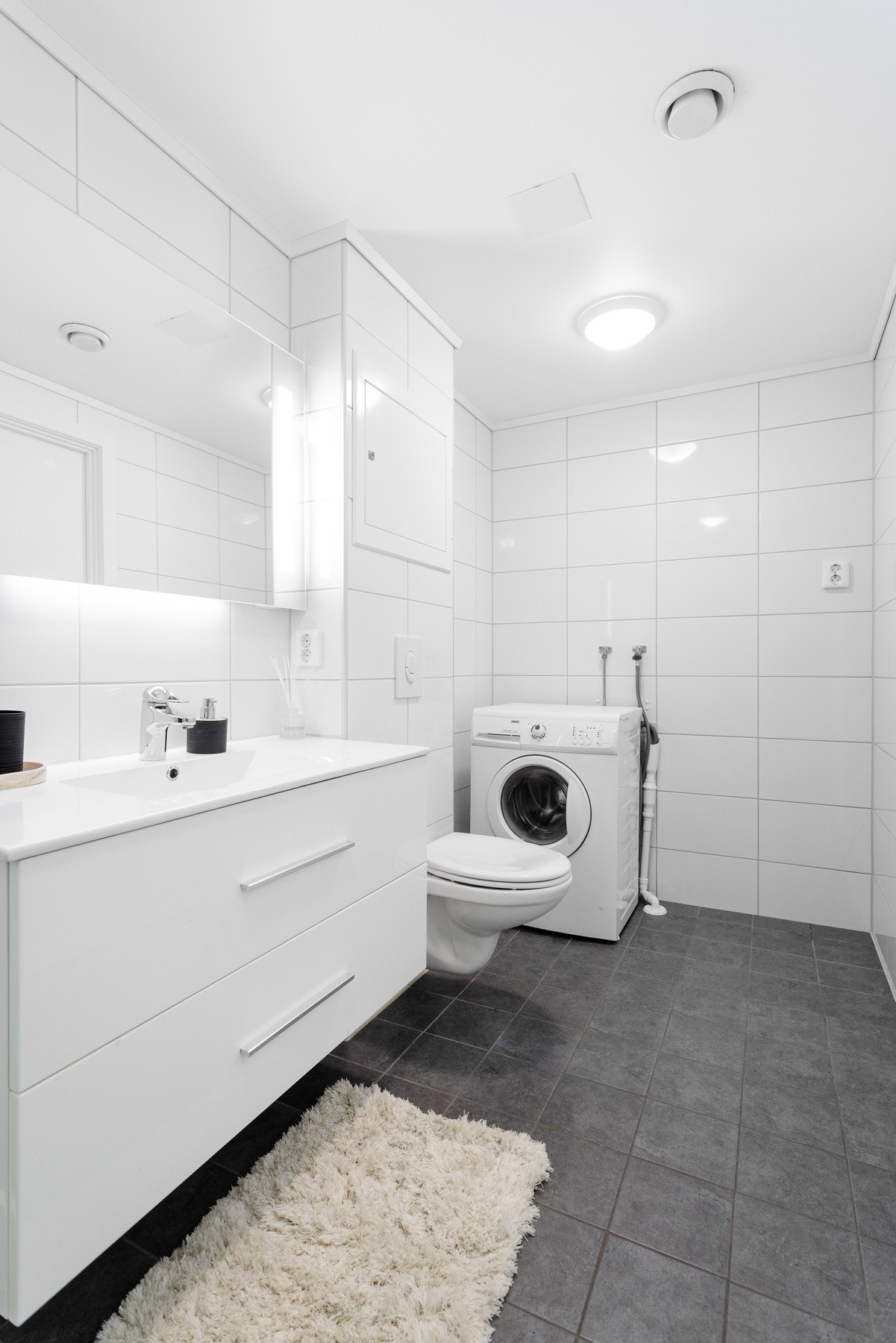 Rommet har elektriske varmekabler som gir en behagelig gulvtemperatur. Innredningen består av en bred servant med dype skuffer, veggmontert toalett og dusjkabinett. Det er også opplegg for vaskemaskin. Galleribilde