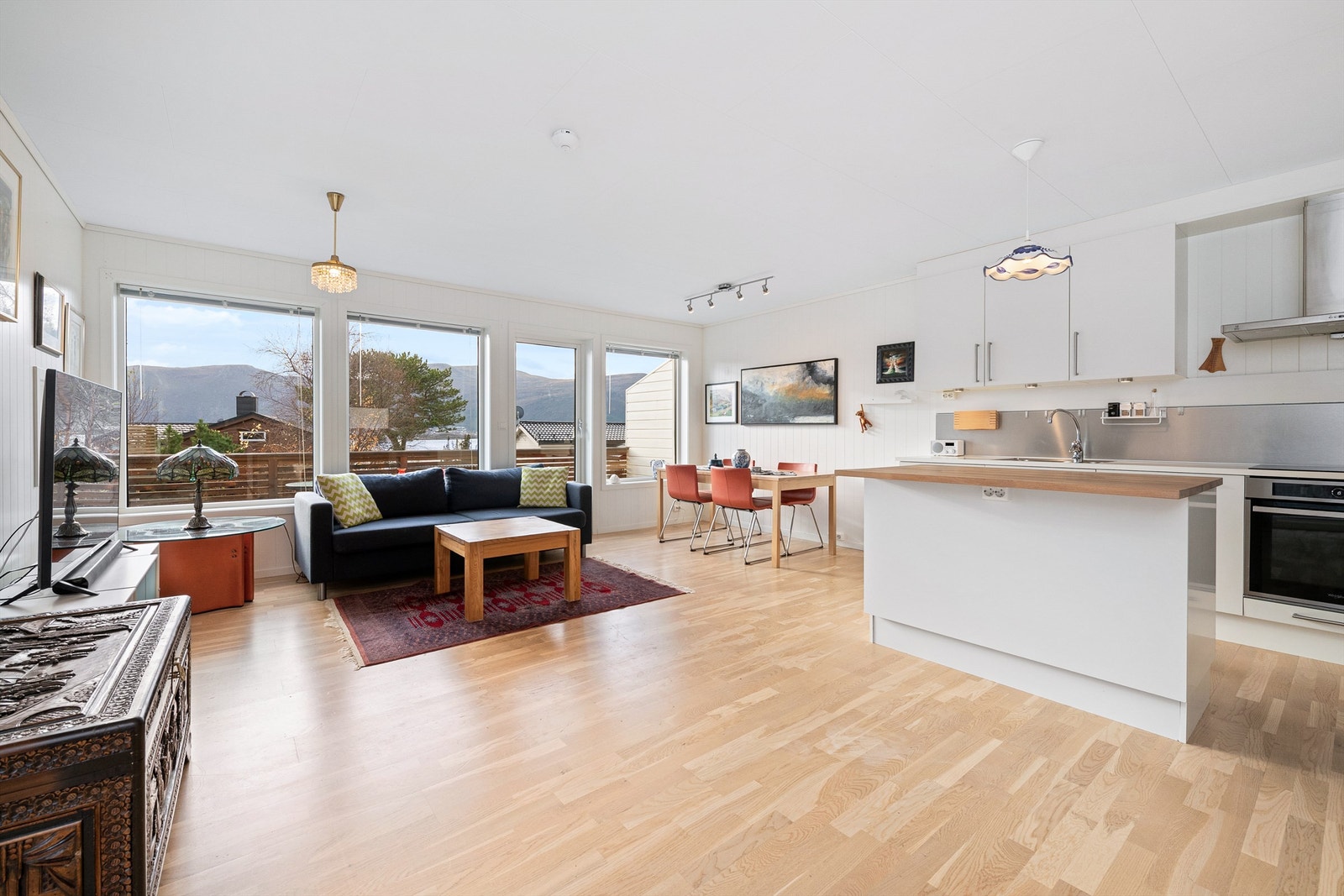 Lys stue med store vinduer og åpen løsning mot kjøkkenet Galleribilde