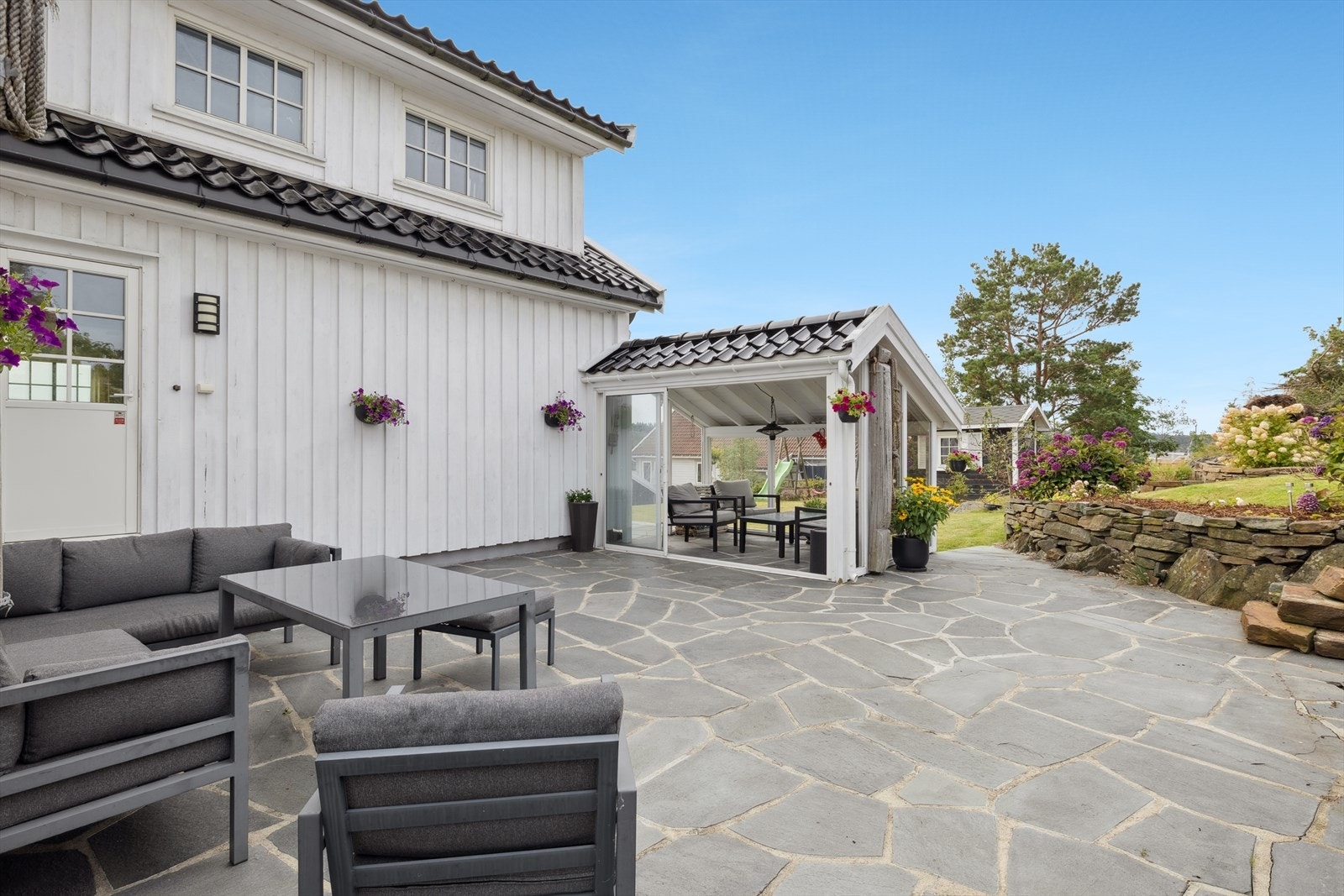 Boligen har en stor tomt med terrasse belagt med skiferstein rundt store deler av huset. Galleribilde