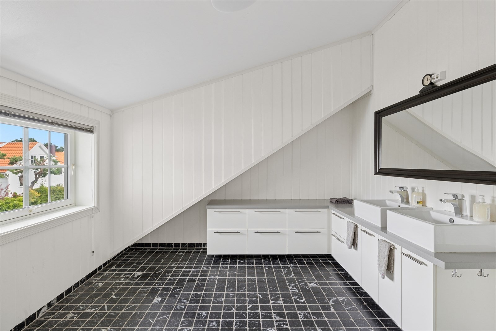 Badet fremstår som moderne og praktisk Rommet er innredet med toalett, skittentøysjakt ned til vaskerom, dusjkabinett og en elegant baderomsinnredning med to servanter - ideelt for en familiehverdag med behov for god plass og funksjonalitet. Galleribilde