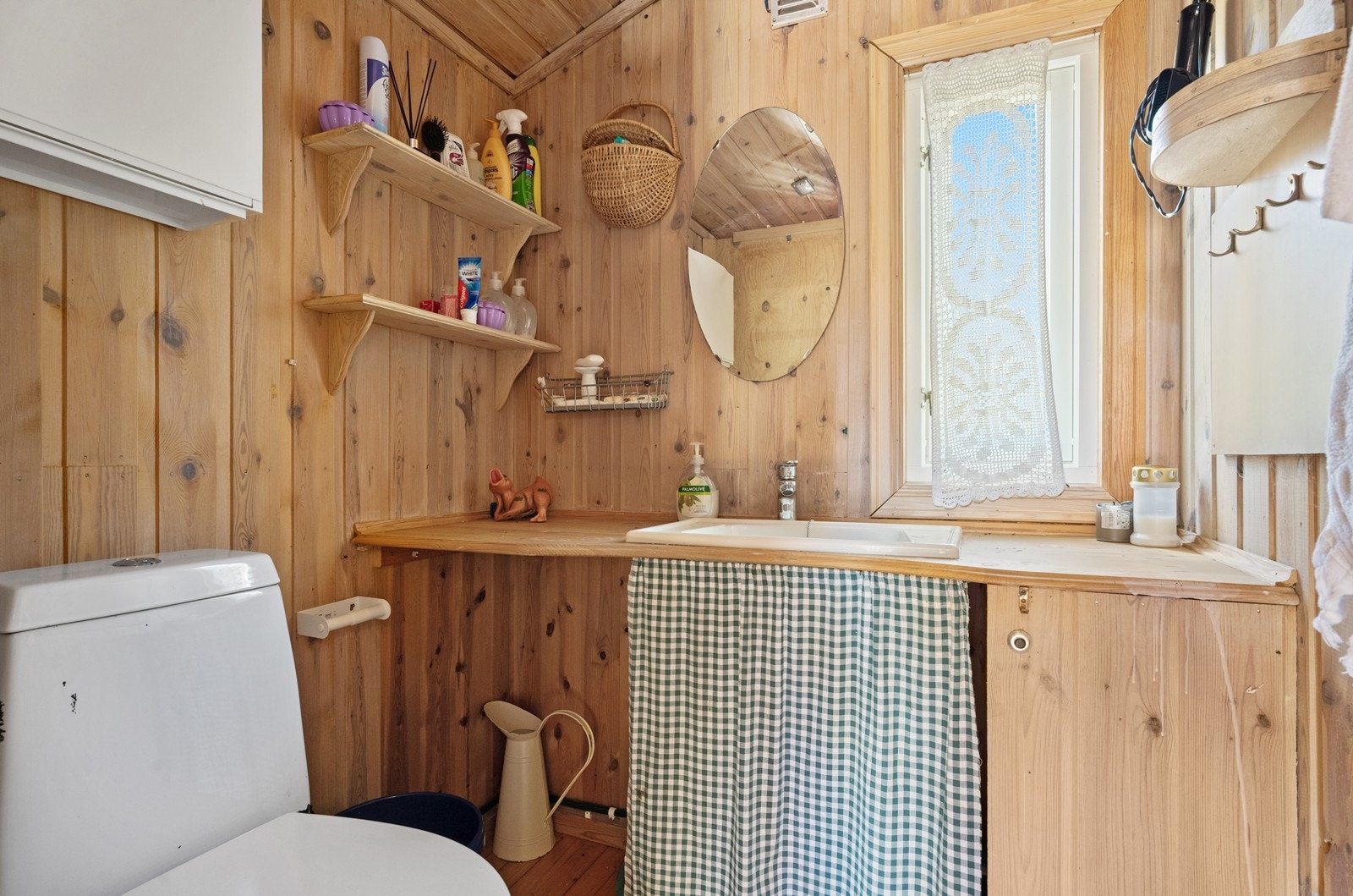 Toalettrom med servant og gulvfestet toalett med tilhørende avfallsbeholder. Galleribilde