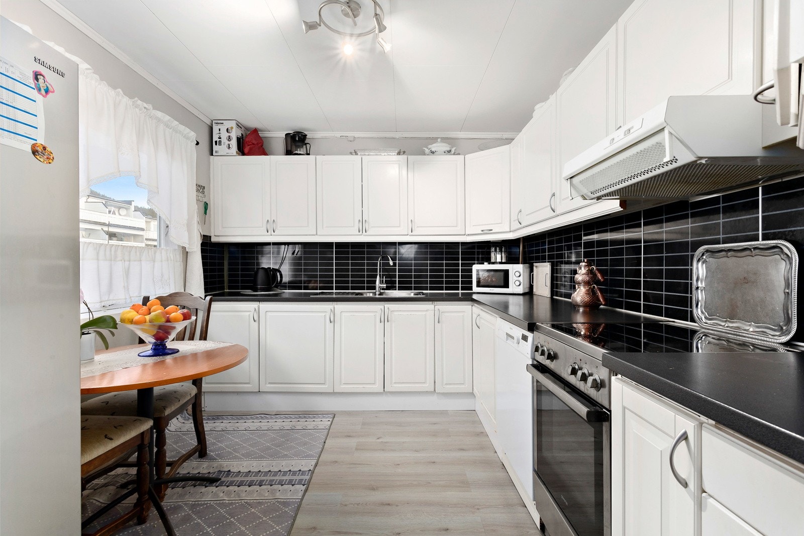 Kjøkkeninnredning med hvite profilerte flater, og godt med skap- og benkeplass. Galleribilde