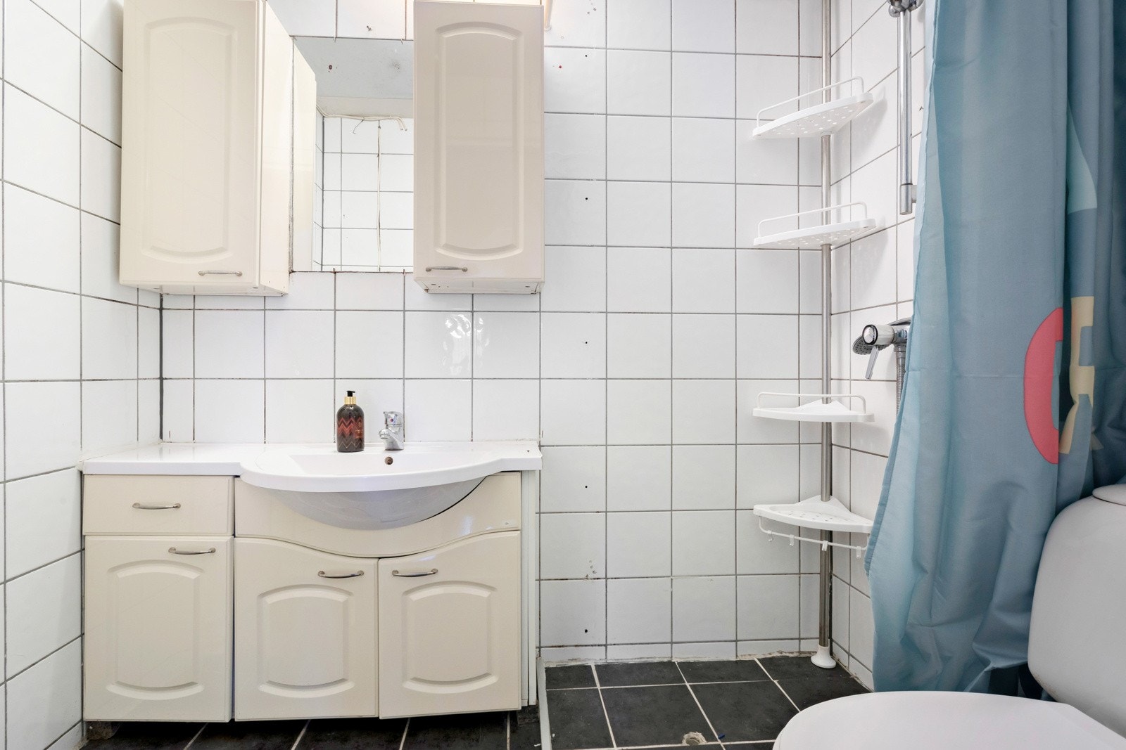 Flislagt bad i underetasje med vegghengt servant, overskap og dusjsone. Galleribilde