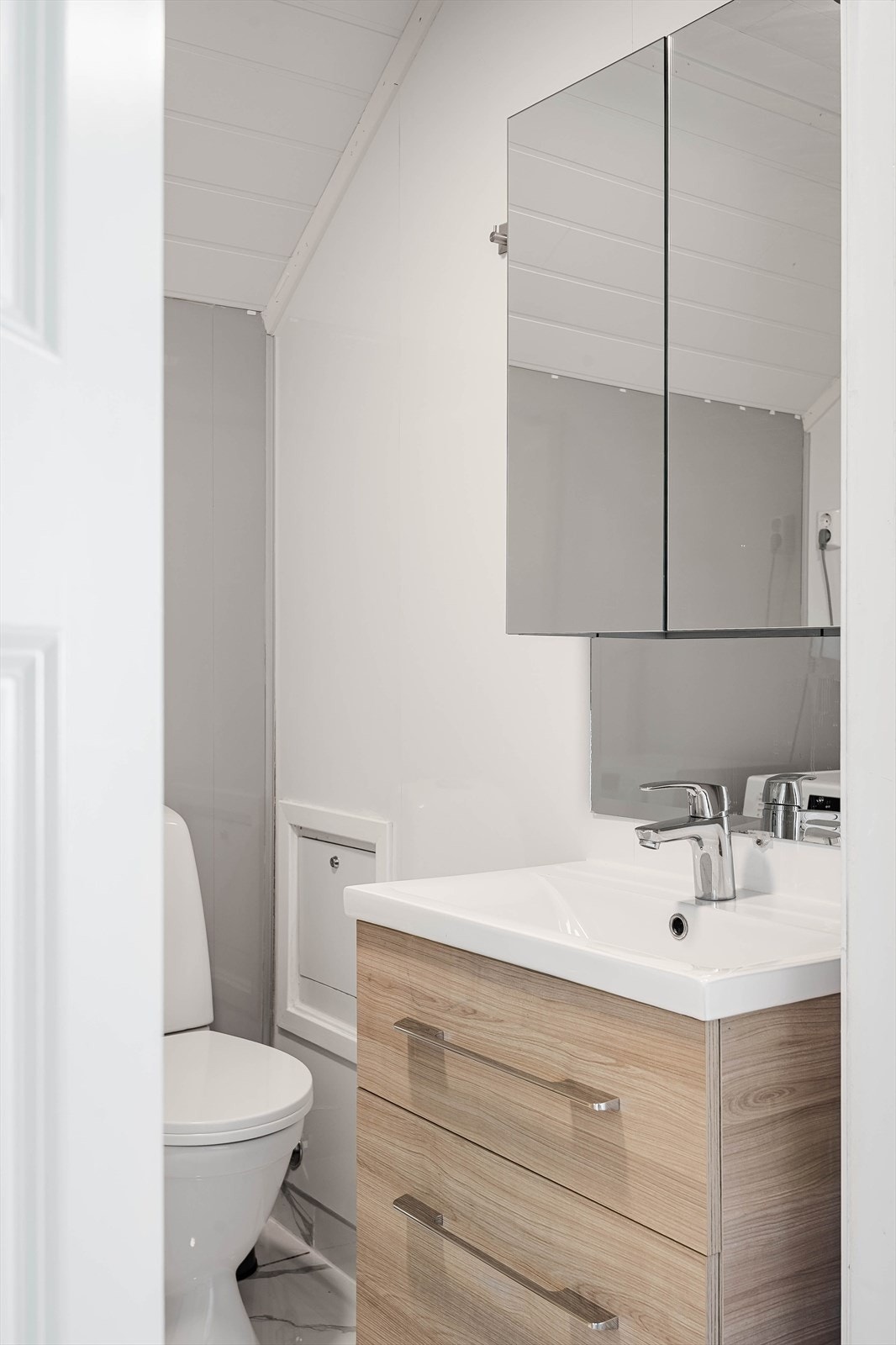 Pen baderomsinnredning med skuffer og heldekkende servant, vegghengt speilskap over. Baderommet er også utstyrt med dusjkabinett og gulvstående toalett. Galleribilde