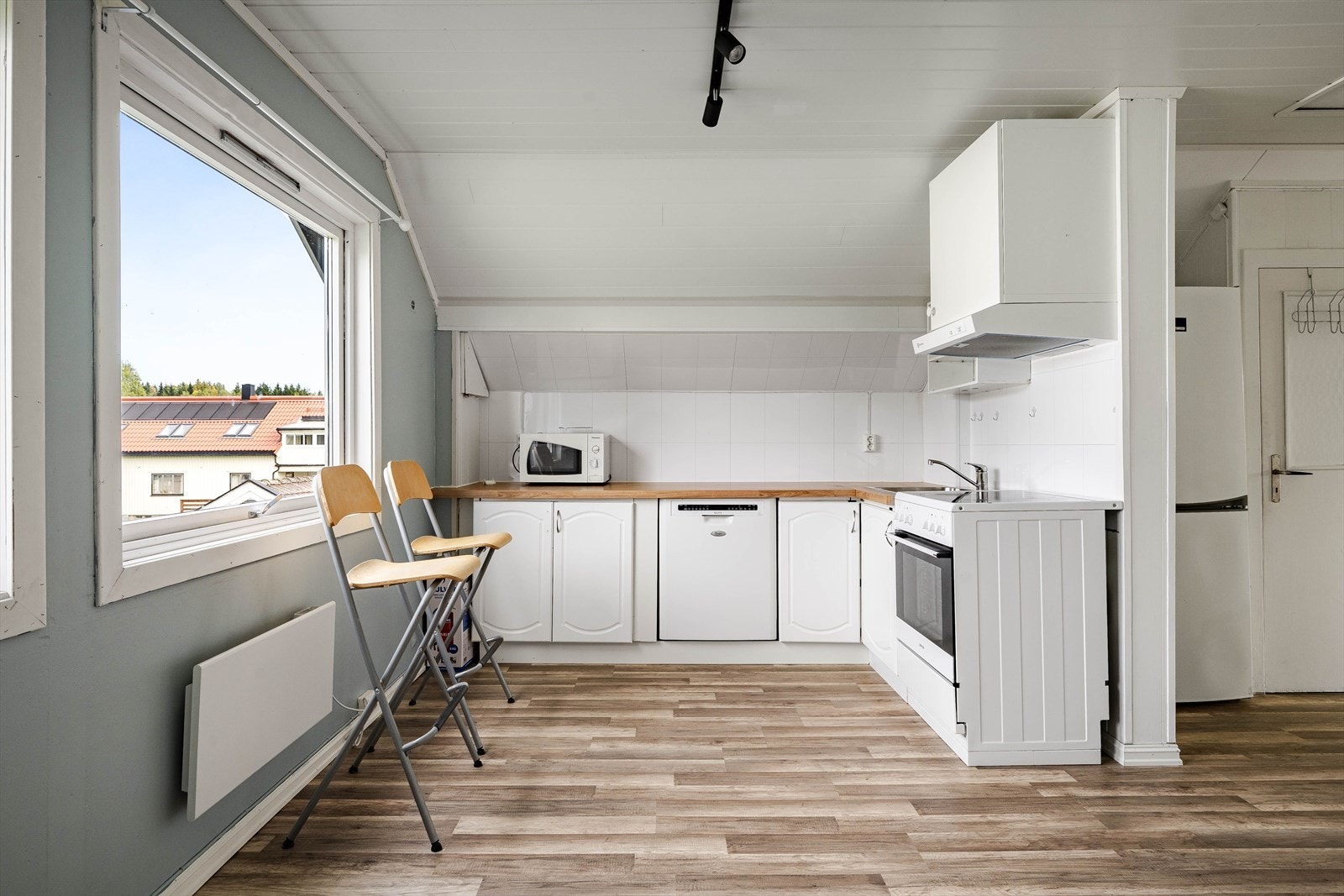 Lys kjøkkeninnredning med profilerte fronter og benkeplate av laminert tre med nedfelt oppvaskkum. Praktisk med lyse plater i benkeryggen og kjøkkenventilator med avtrekk ut. Galleribilde