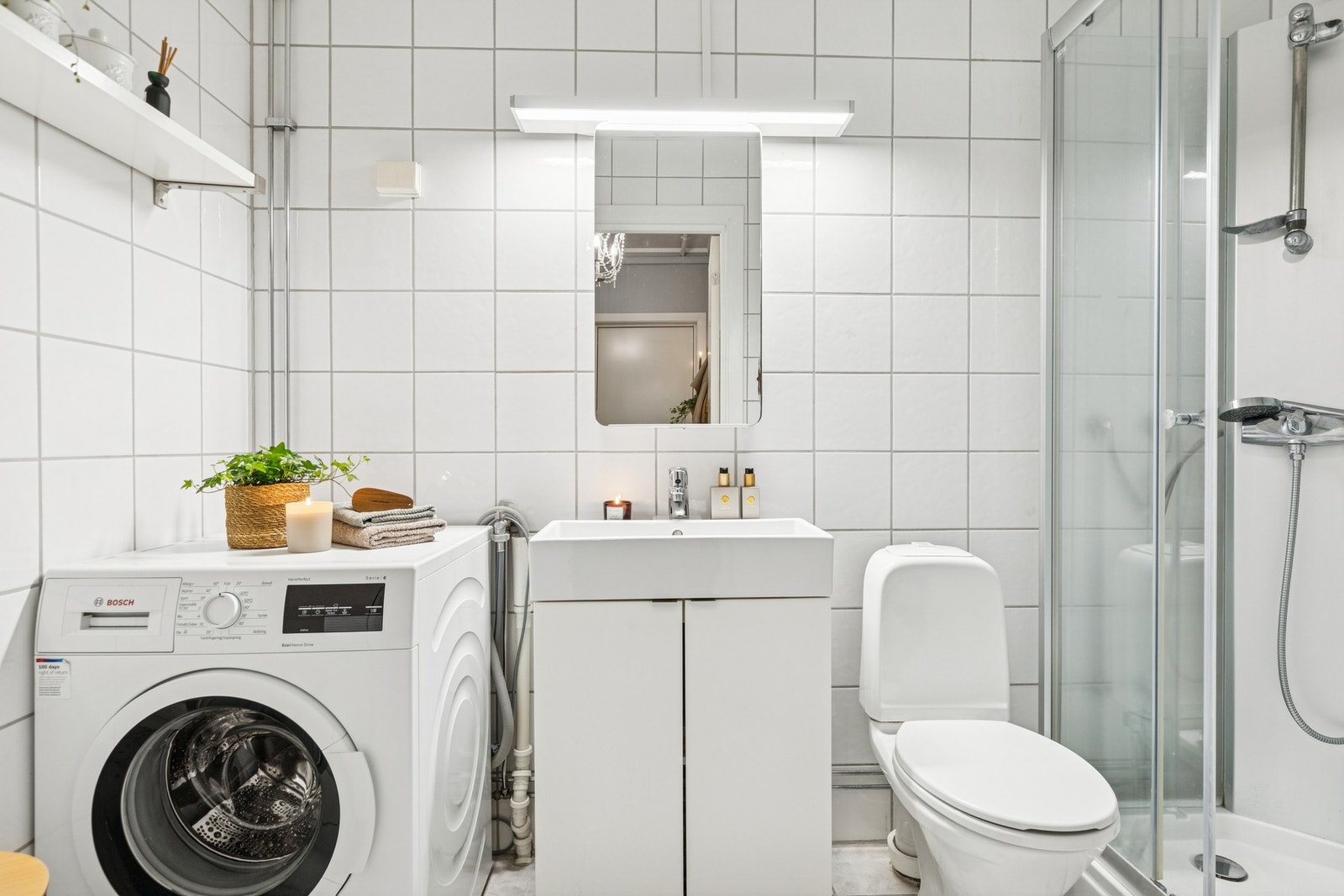 Badet har vegghengt servantskap med plass til oppbevaring og heldekkende servant. Her får du opplegg for vaskemaskin. Galleribilde