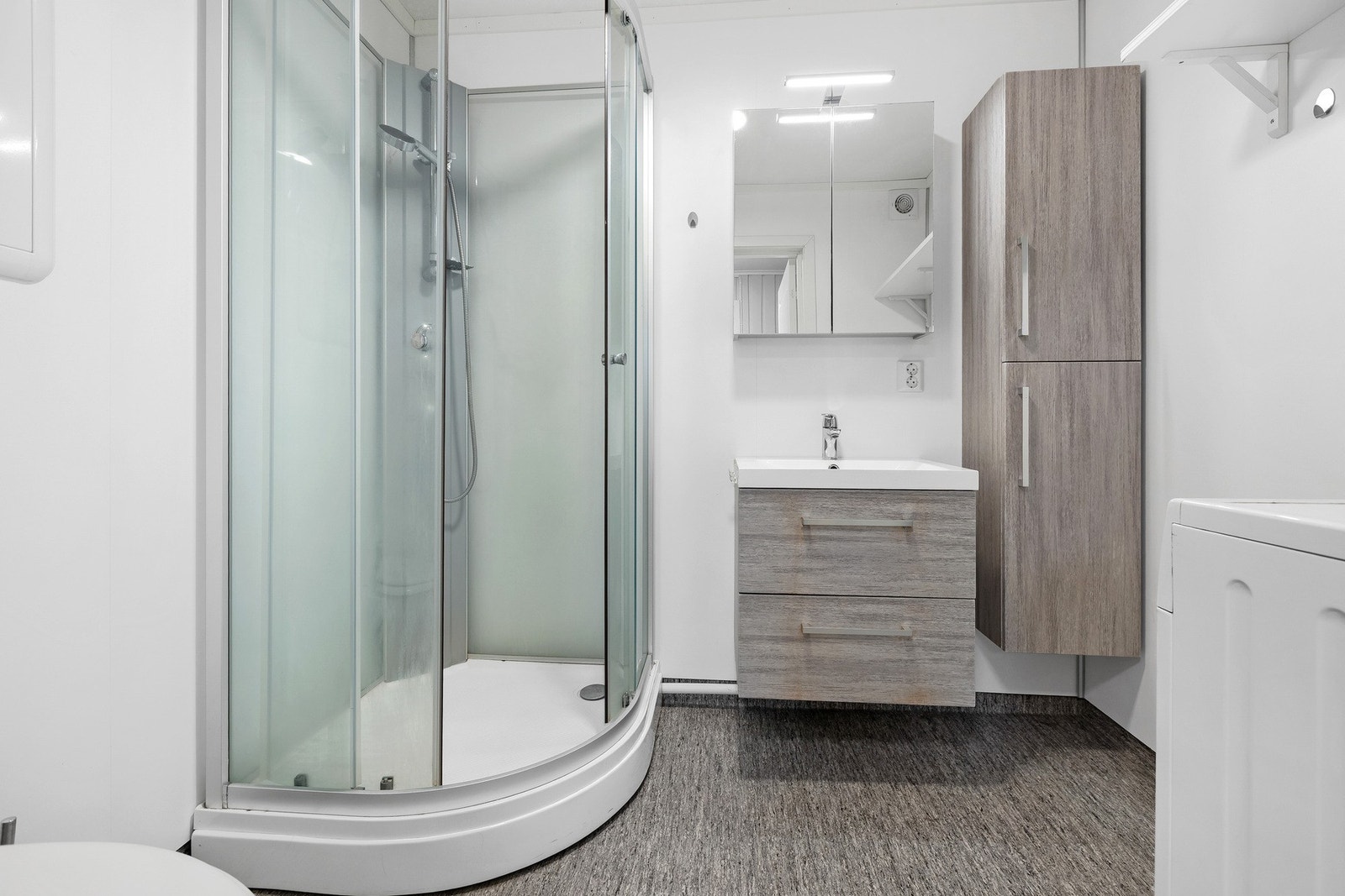 Badet i leiligheten ha vegger kledd med baderomsplater, mens taket er malt og gulvet har vinylbelegg med varmekabler. Galleribilde