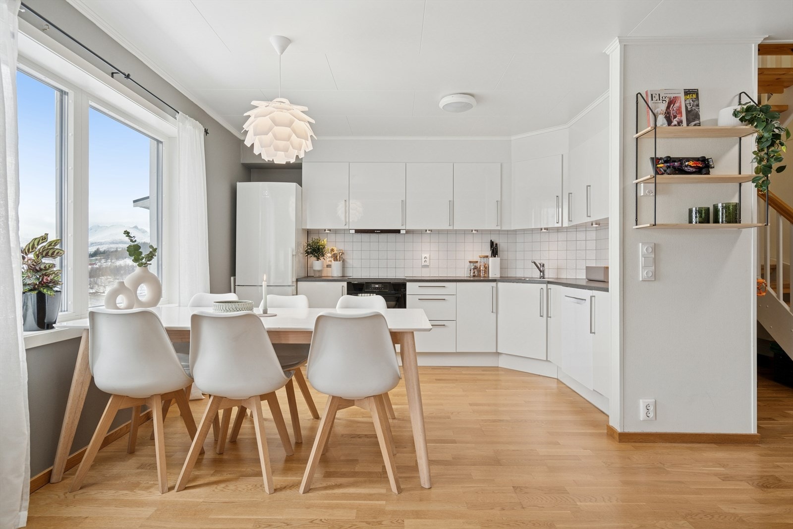 Kjøkkenet har en stilren innredning med hvite slette fronter, benkeplate i laminat og fliser på vegg over benk. Hvitevarene medfølger. Galleribilde