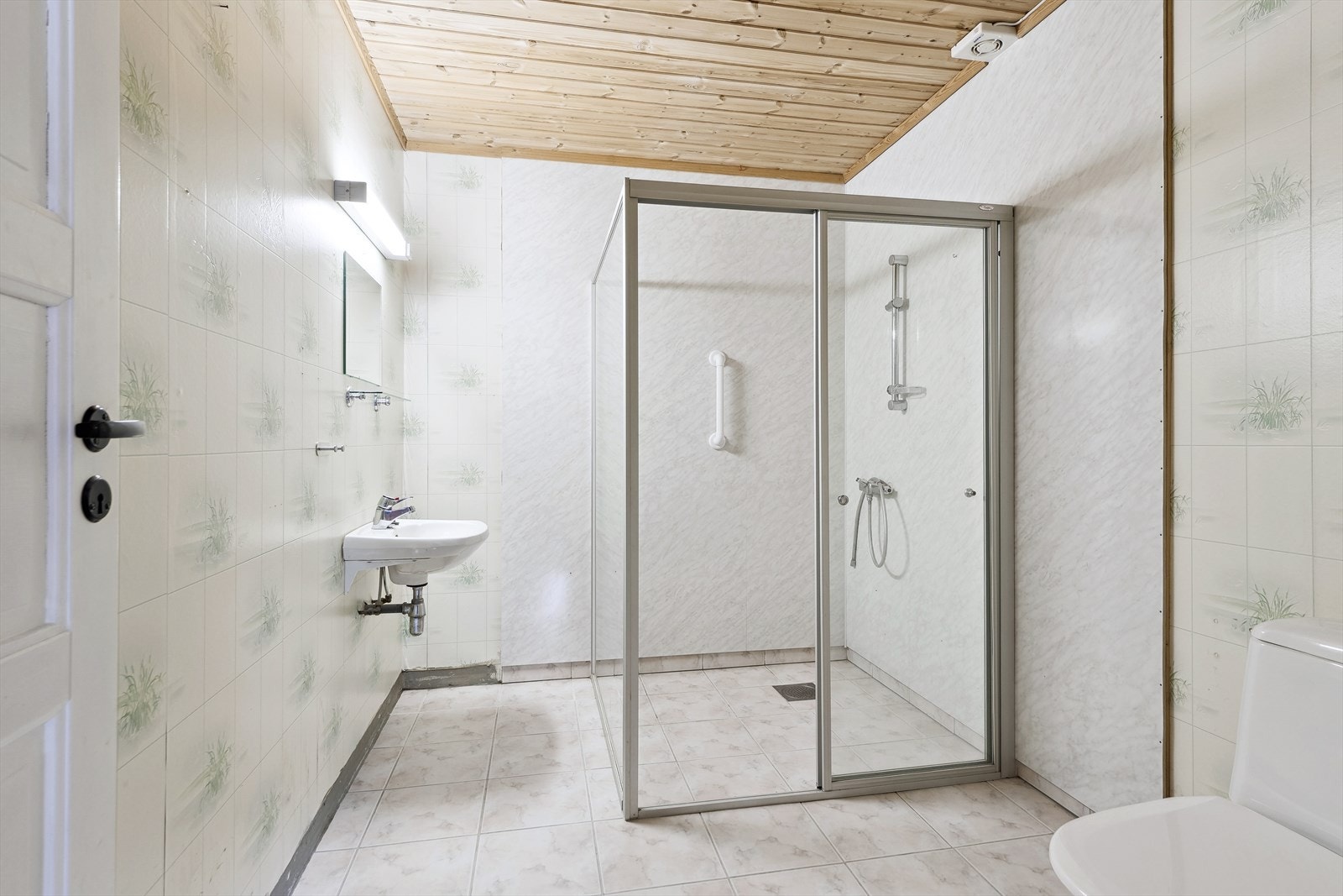 Bad/wc nede med fliser på gulv og våtromstapet. Galleribilde