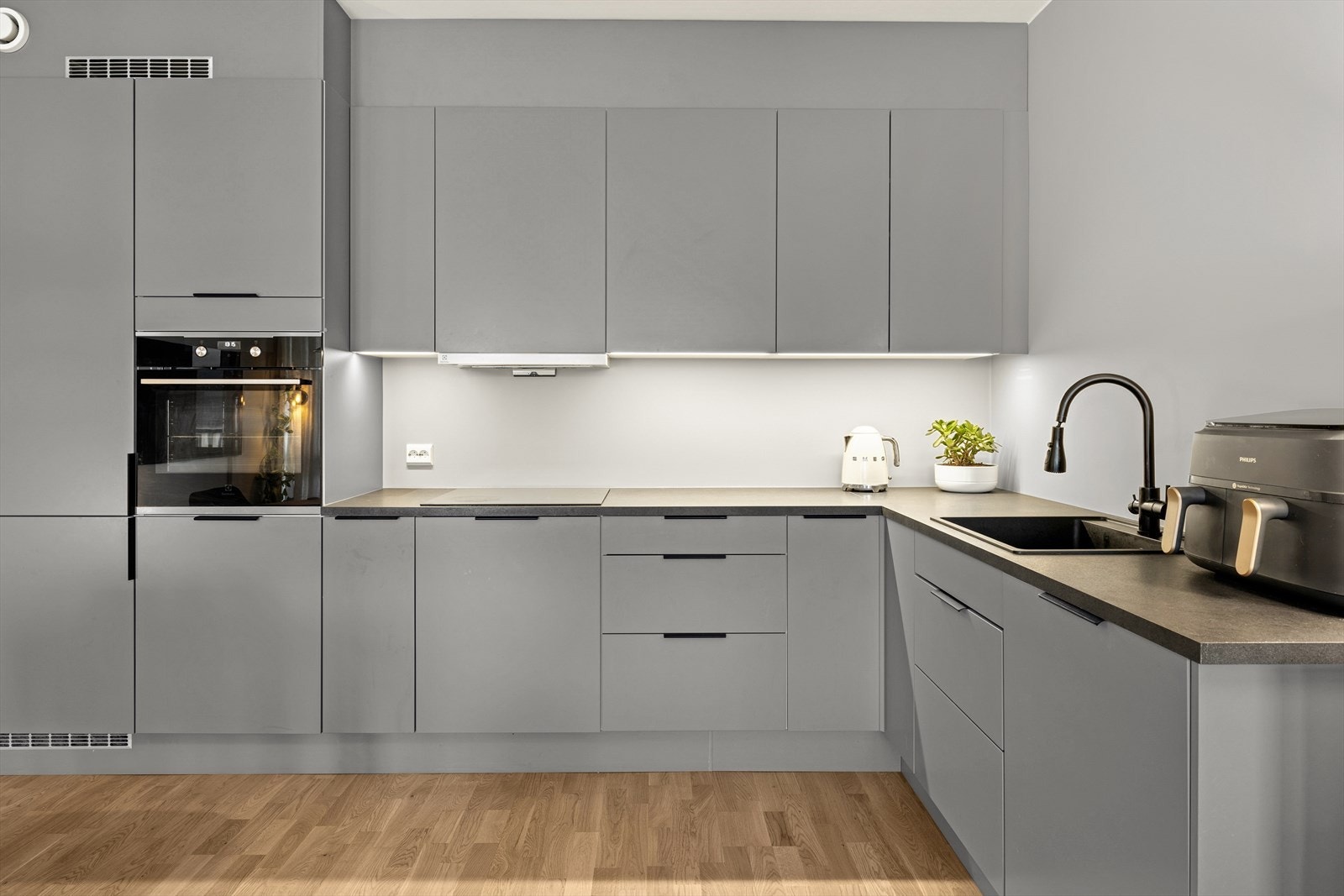 Moderne kjøkken med innredning av laminerte skrog, glatte fronter og en benkeplate av laminat. Galleribilde