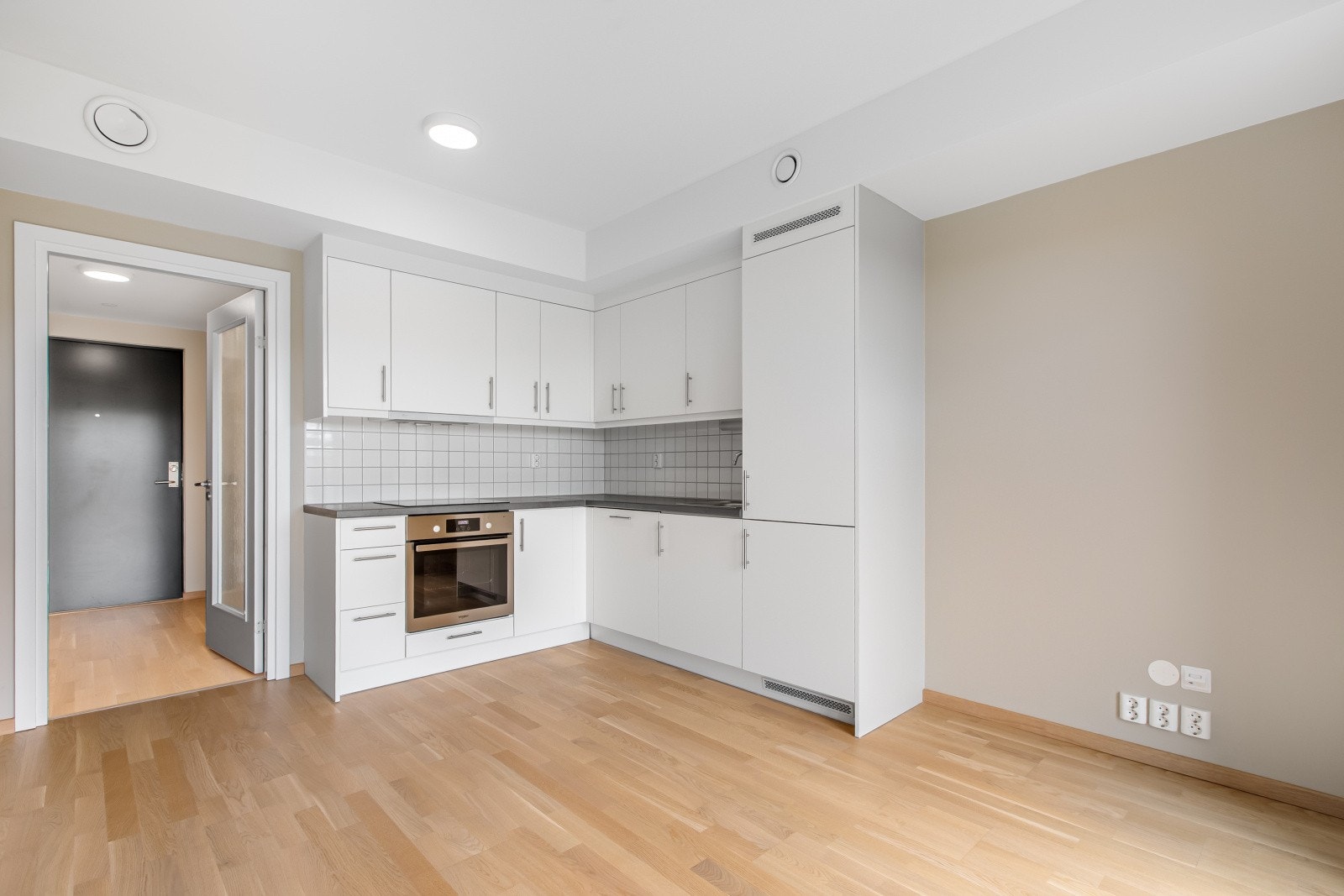 Klassisk kjøkkeninnredning med hvitevarer som komfyr, platetopp, oppvaskmaskin og kombinert kjøl/frys. Galleribilde