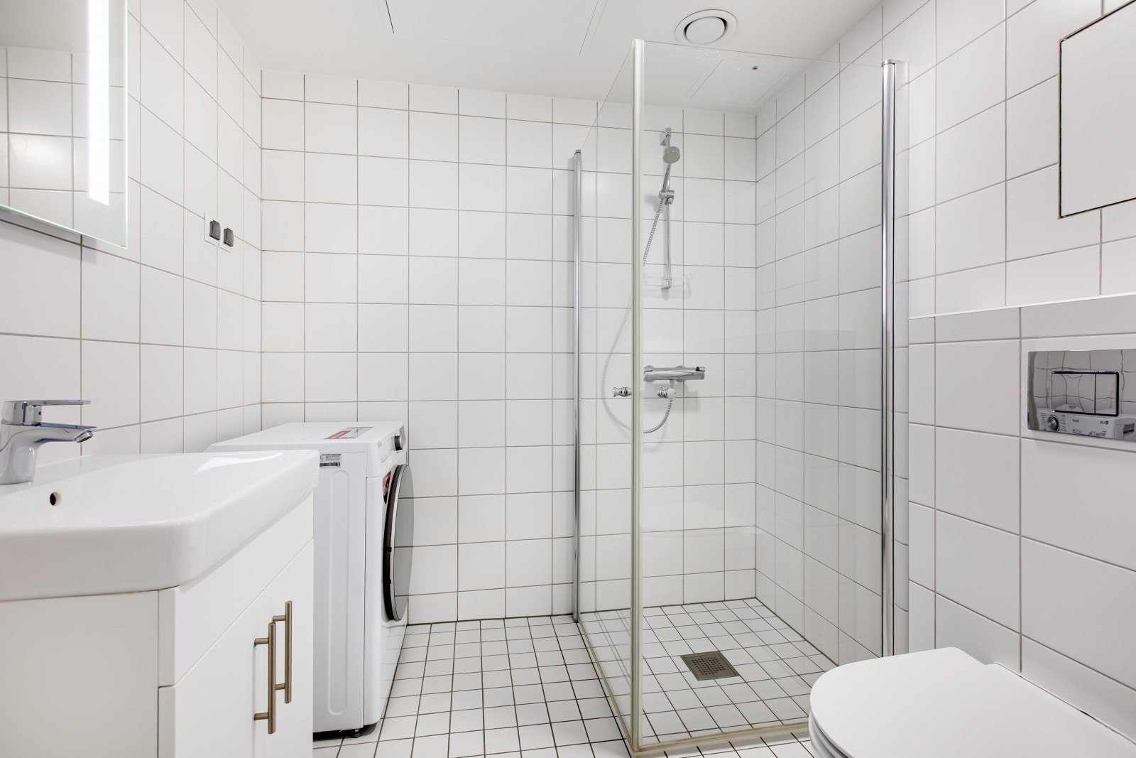 Leiligheten har et romslig, flislagt baderom med varme i gulv. Badet er innredet med vegghengt toalett, dusjnisje med innfellbare glassdører, servantinnredning og opplegg for vaskemaskin og tørketrommel i søyle. Galleribilde