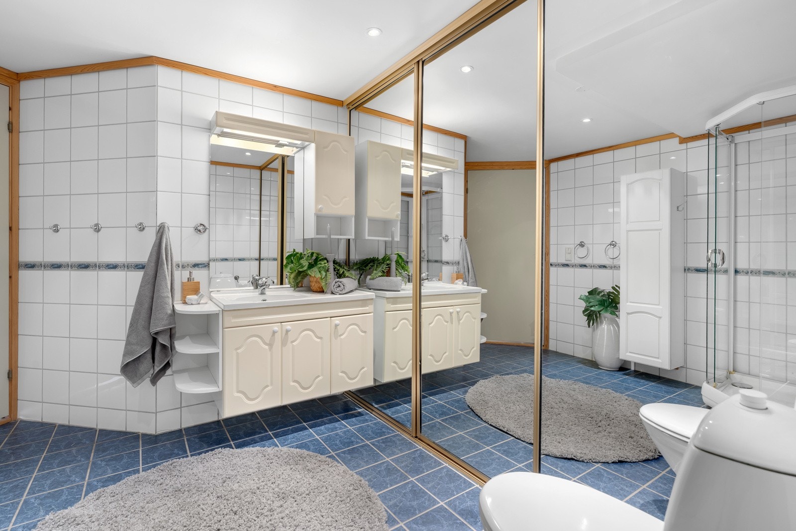 Stort, flislagt bad med skyvedører til utslagsvask og vaskemaskin. Galleribilde