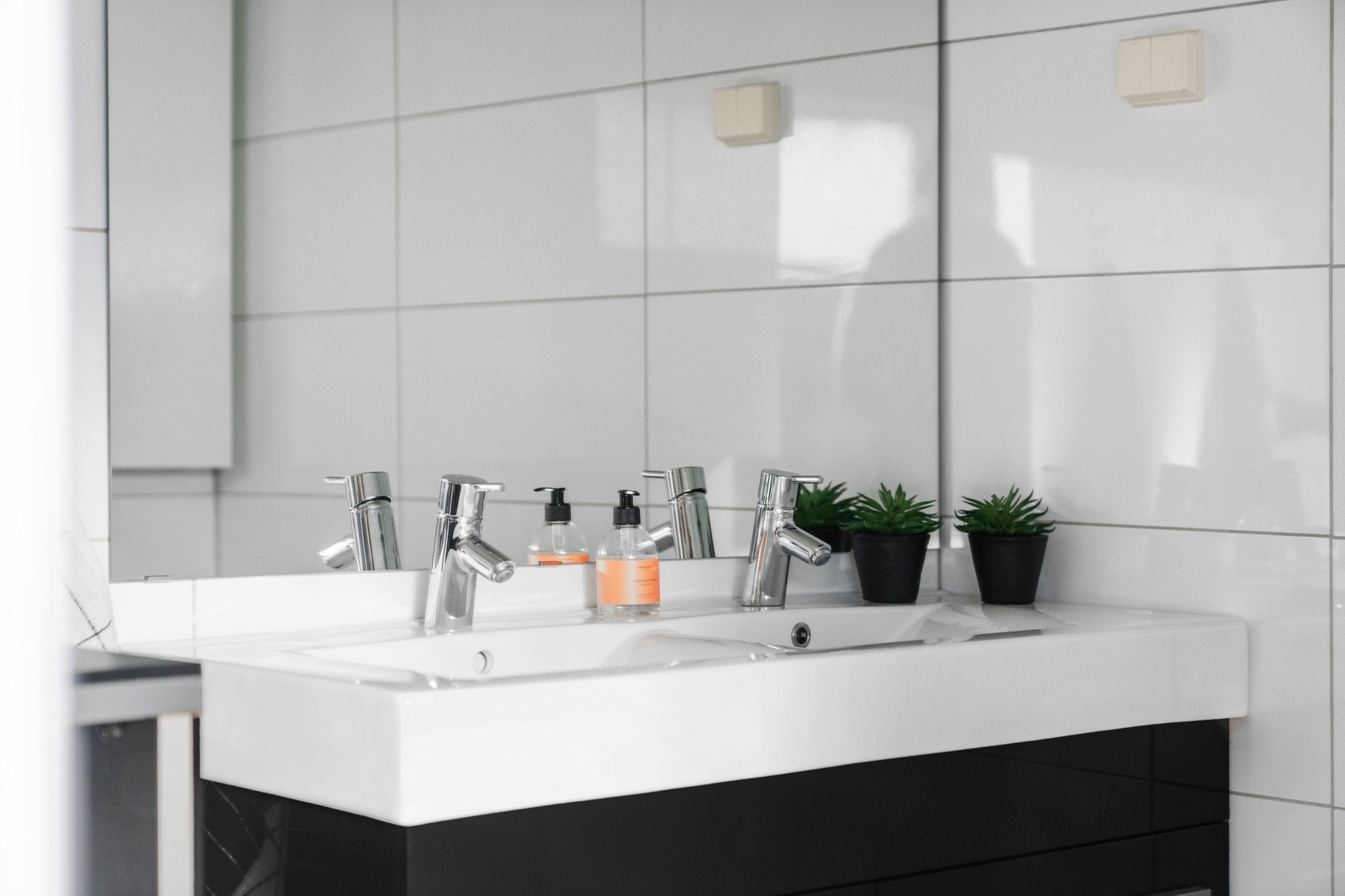 Begge badene er utført med moderne, grå fliser på gulv og hvite fliser på vegg Galleribilde