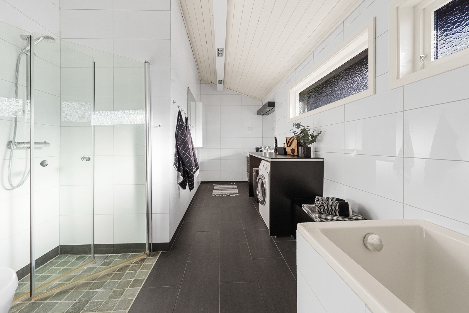 Det største baderommet har dobbel servant i innredning, vegghengt toalett, badekar og en romslig dusjnisje med glassvegger Galleribilde