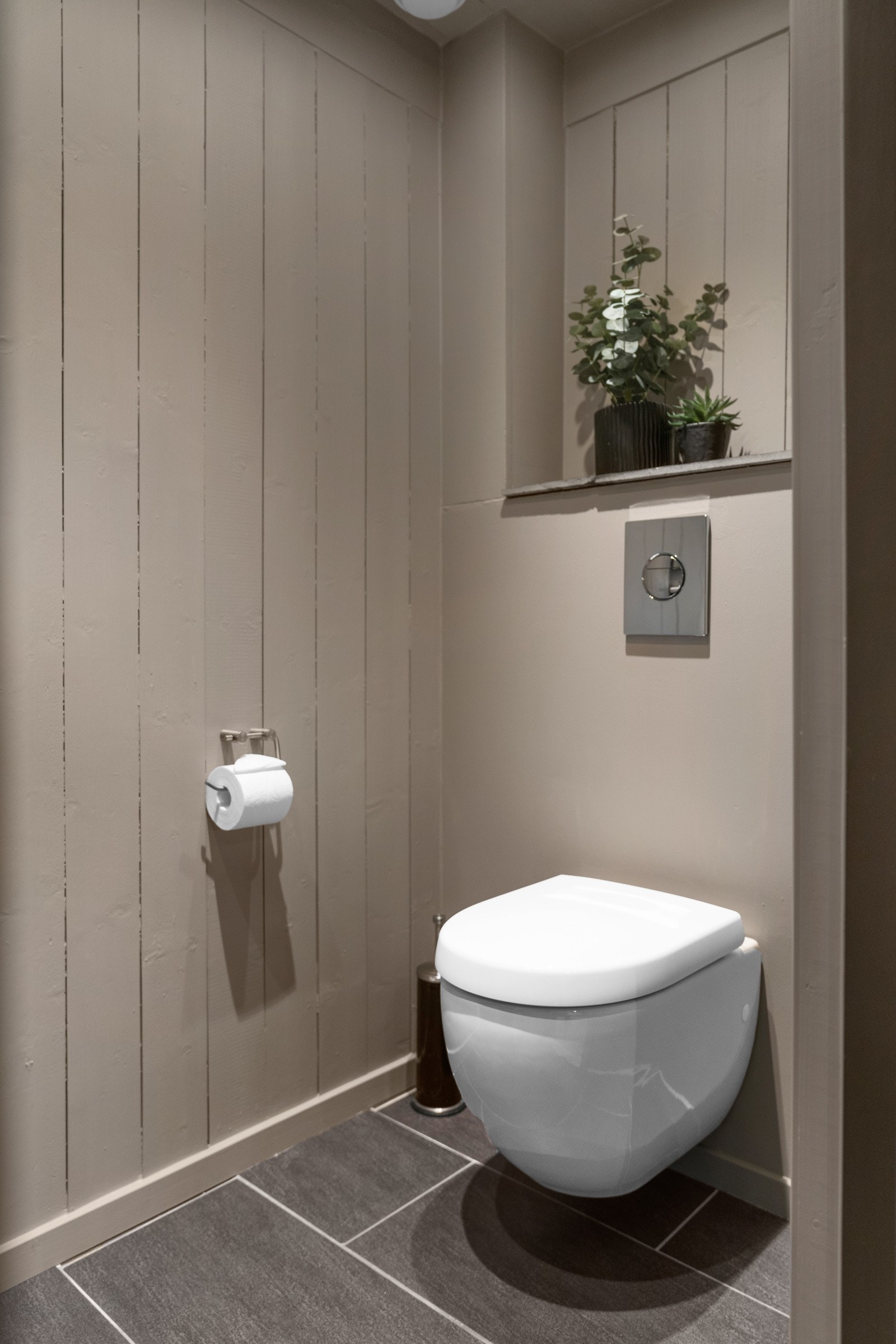 Praktisk toalettrom som inneholder vegghengt toalett, servant med innredning og speil Galleribilde