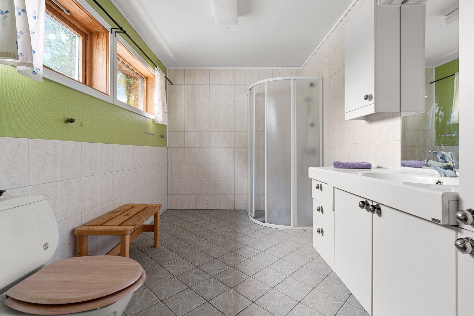 Bad med fliselagt gulv, hjørnedusj, vegghengt servant og gulvvarme. Galleribilde