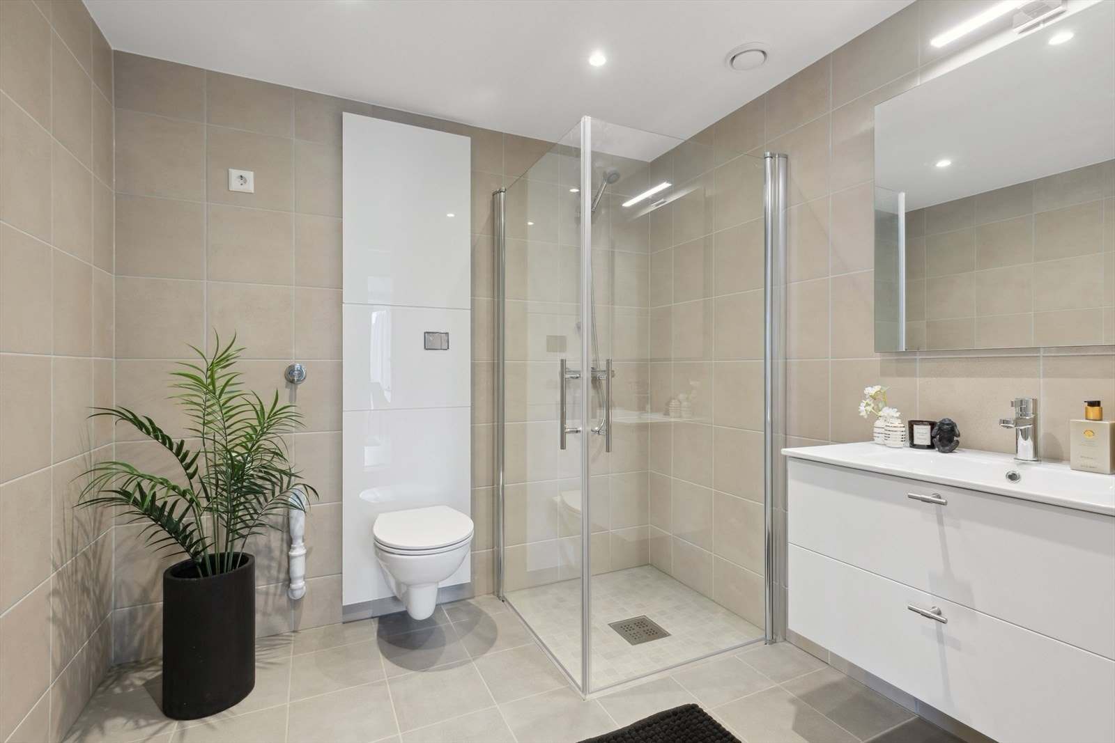 Pent, flislagt bad med innfellbare dusjvegger, veggfestet wc og hvit innredning. Galleribilde