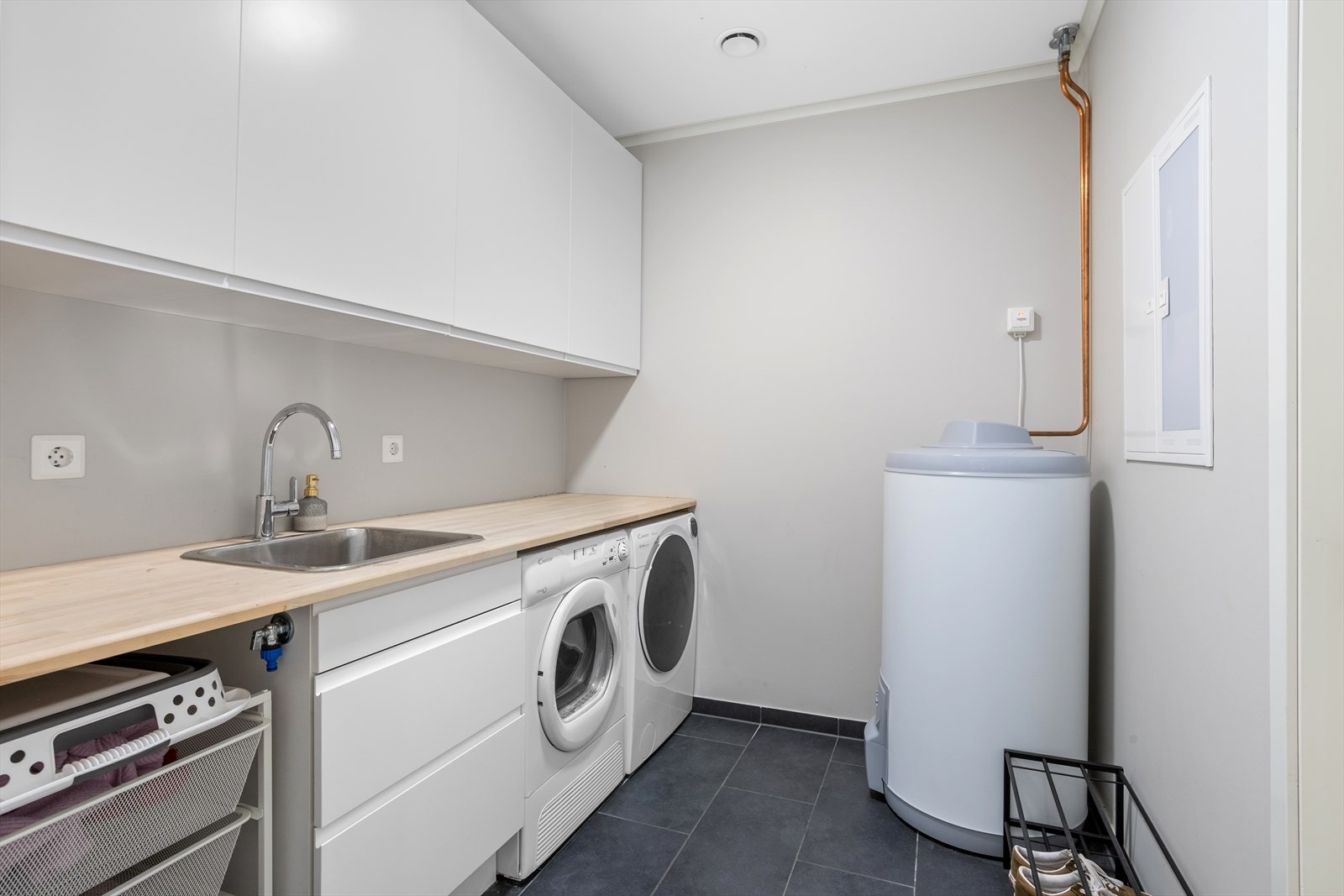 Vaskerommet ligger innenfor badet og har dør til garasjen. Dør mellom badet og vaskerommet holder rommene adskilt. Også i dette rommet er det slitesterke gulvfliser med varmekabler. Galleribilde