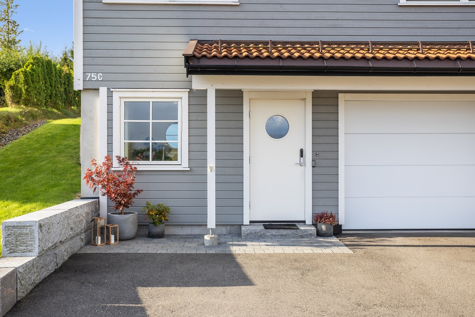 Eiendommen har videre en asfaltert gårdsplass med belegningsstein foran inngangspartiet og asfaltert sone helt frem til innkjøringen til den integrerte garasjen. Galleribilde